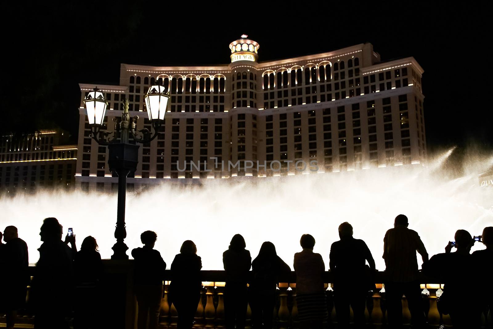 Night scene with silhouettes of people admiring the Bellagio fountains spectacle at Las Vegas