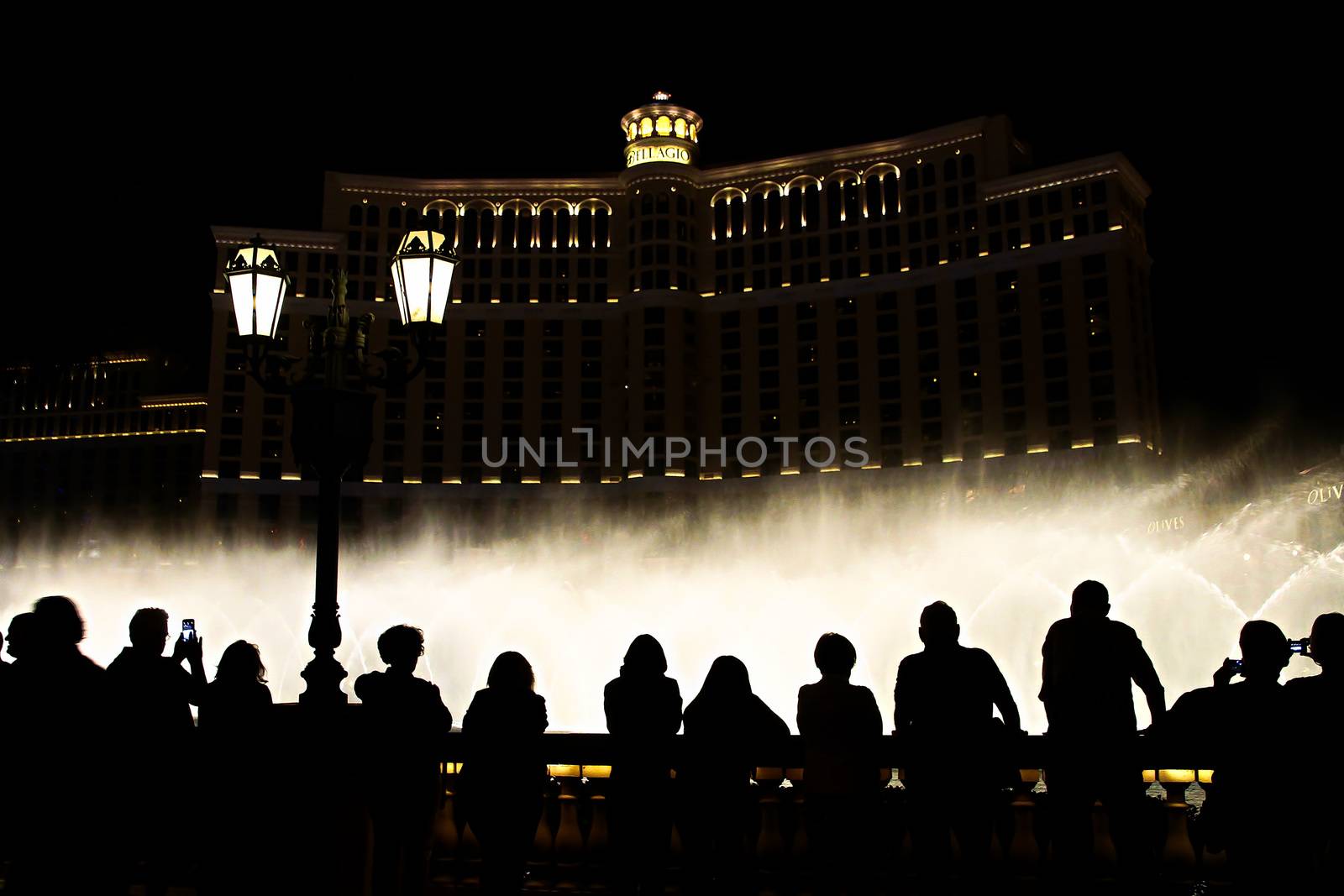 Night scene with silhouettes of people admiring the Bellagio fountains spectacle at Las Vegas by USA-TARO