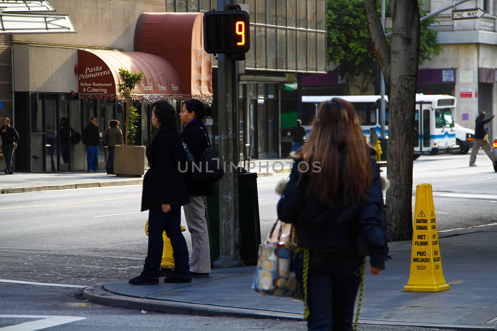 Los Angeles,CA/USA - Nov,03,2018 : Back view of young girls walking at an intersection and women waiting for a signal