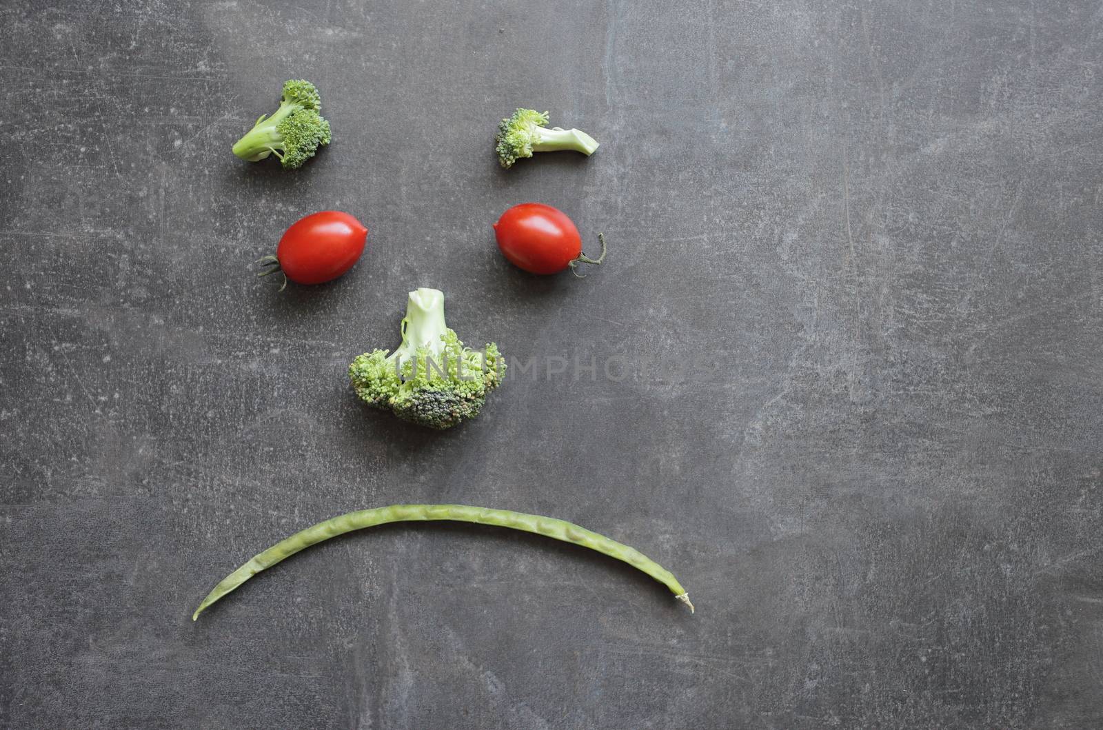 Sad emoticon made from fresh vegetables cherry tomatoes broccoli and green beans by selinsmo