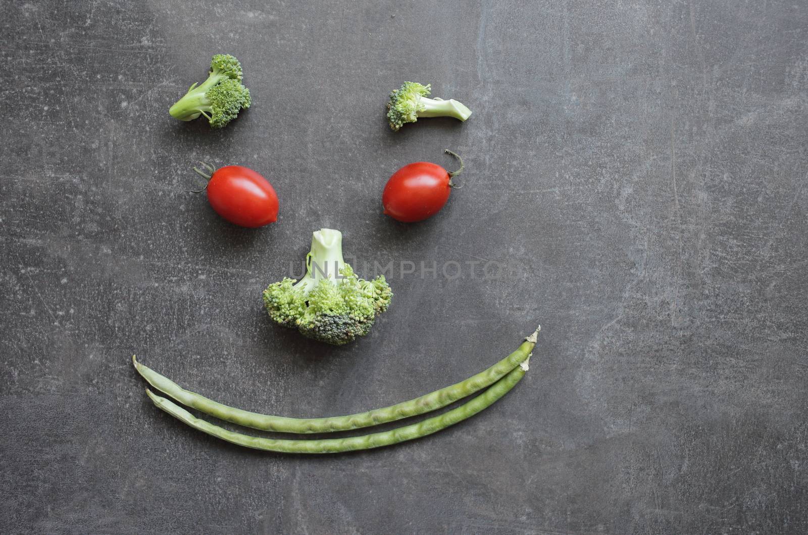 Smiling emoticon of fresh vegetables cherry tomatoes broccoli and green beans by selinsmo
