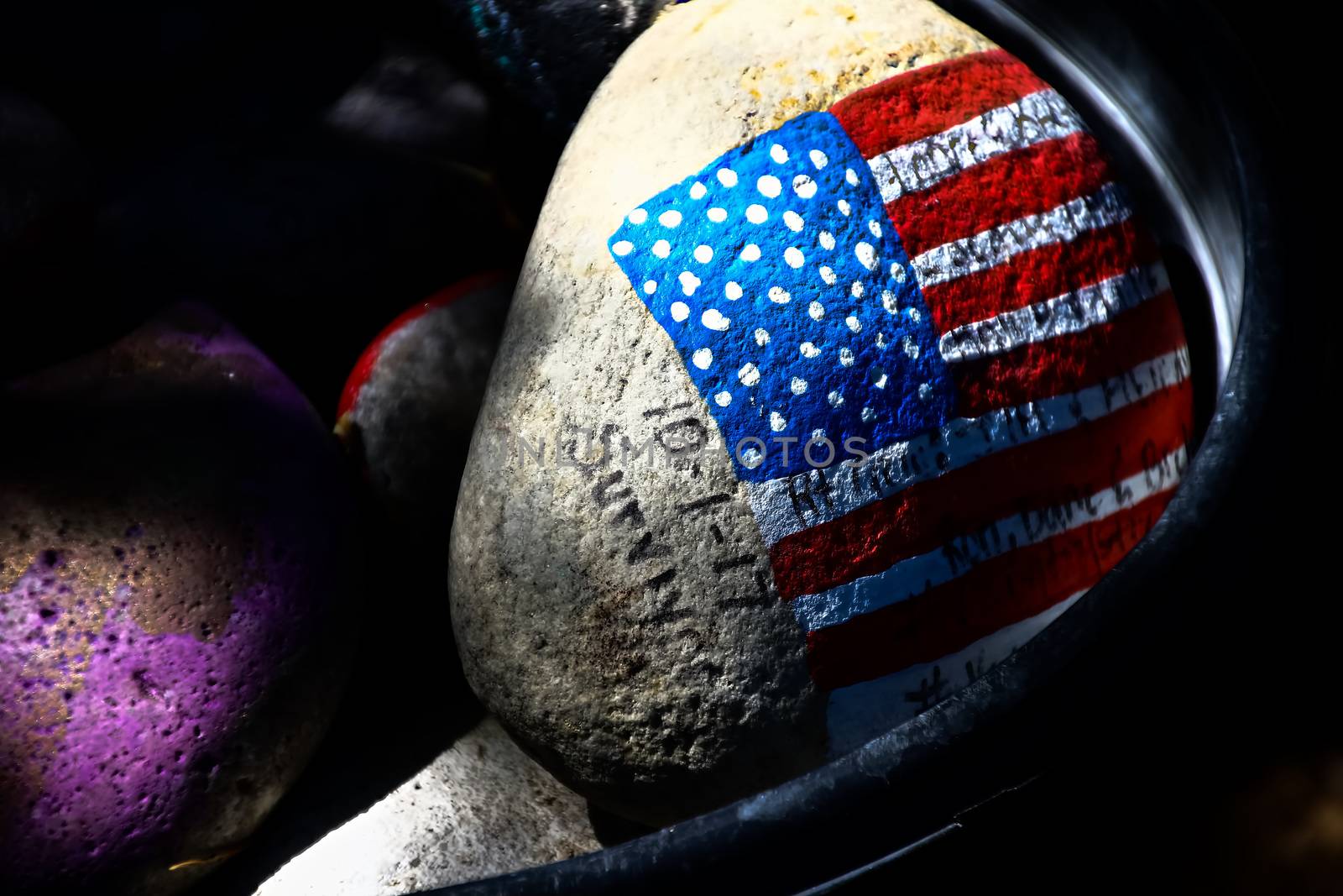 rock painted with the American Flag.American flag painted on a gray stone.Close-up of rock with American flag painted.
