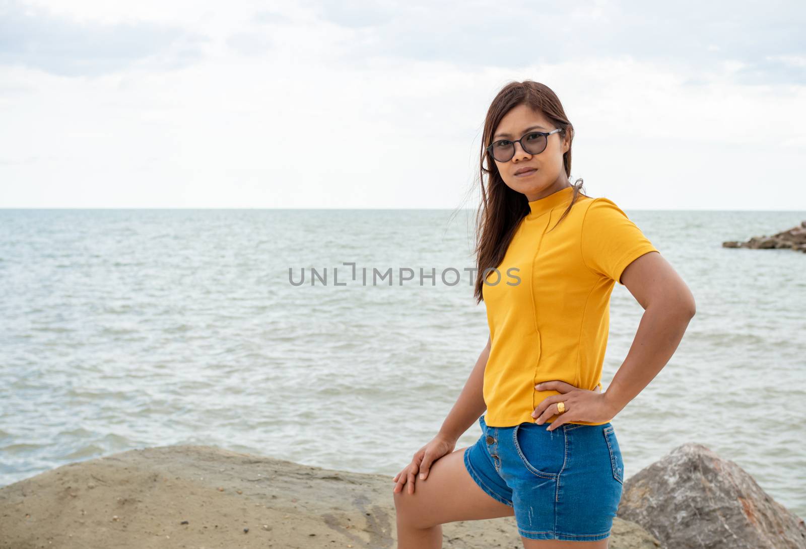 Portrait of a woman standing on a rock with a sea background. by Unimages2527