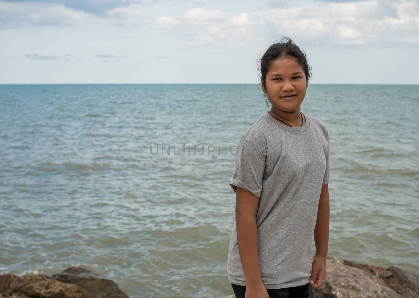 Portrait of a girl standing with a sea background. by Unimages2527