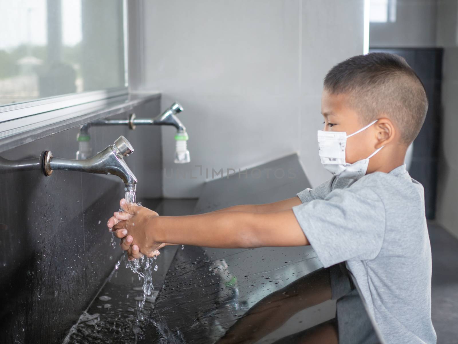 Boy wearing a mask Washing hands in public toilets by Unimages2527