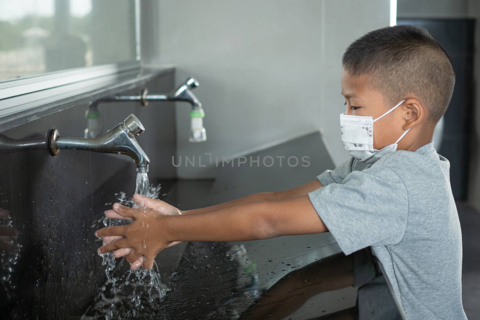 Boy wearing a mask Washing hands in public toilets by Unimages2527