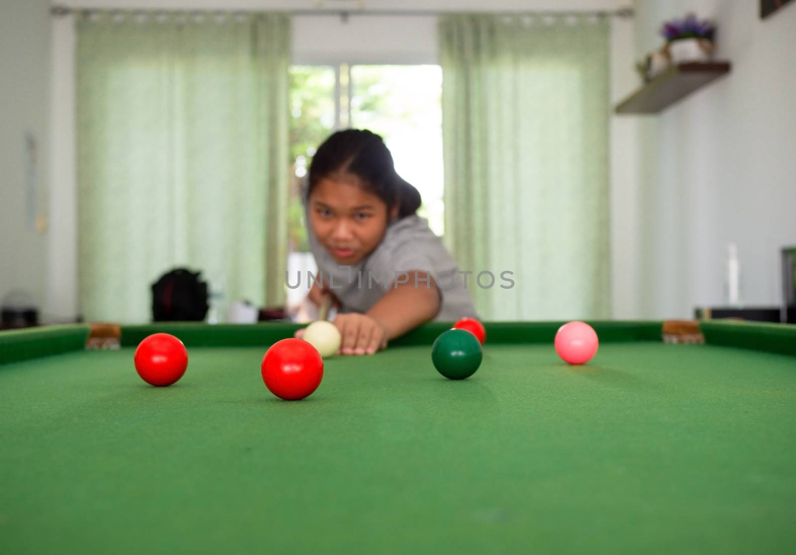 Asian woman playing snooker By aiming at his queue. Focus on the red ball.