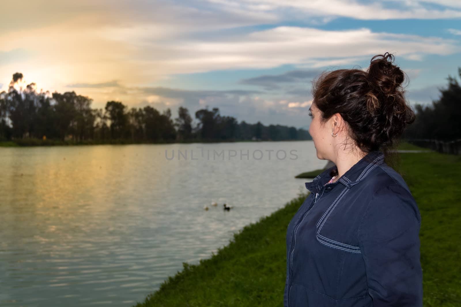 Real woman watching the sunset on a lake. summer