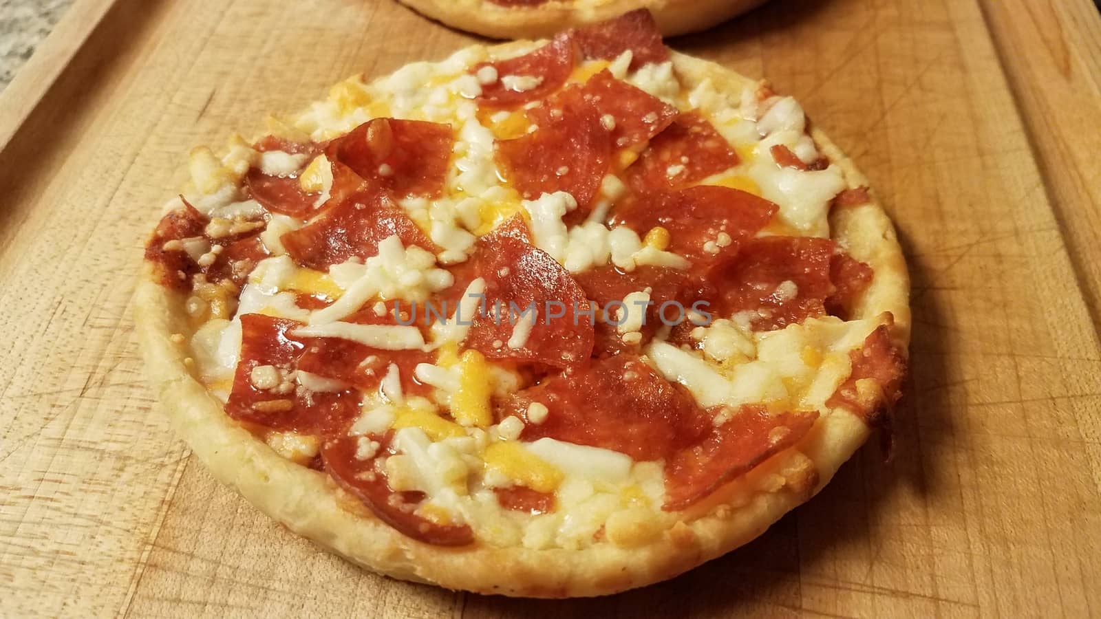 small pepperoni and cheese pizza on wood cutting board