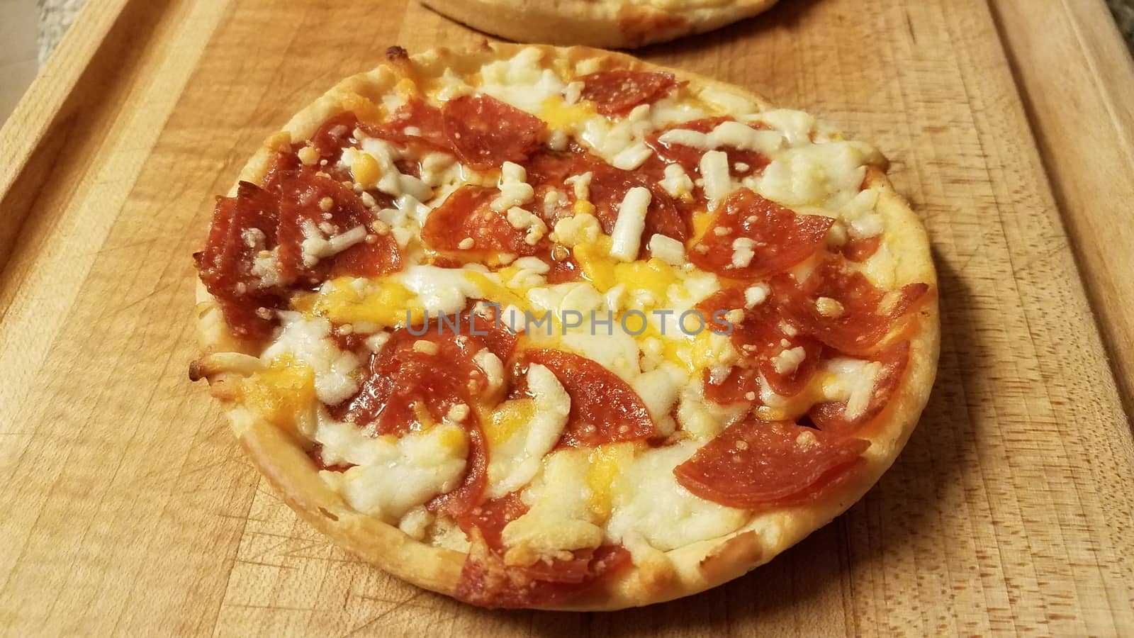 small pepperoni and cheese pizza on wood cutting board