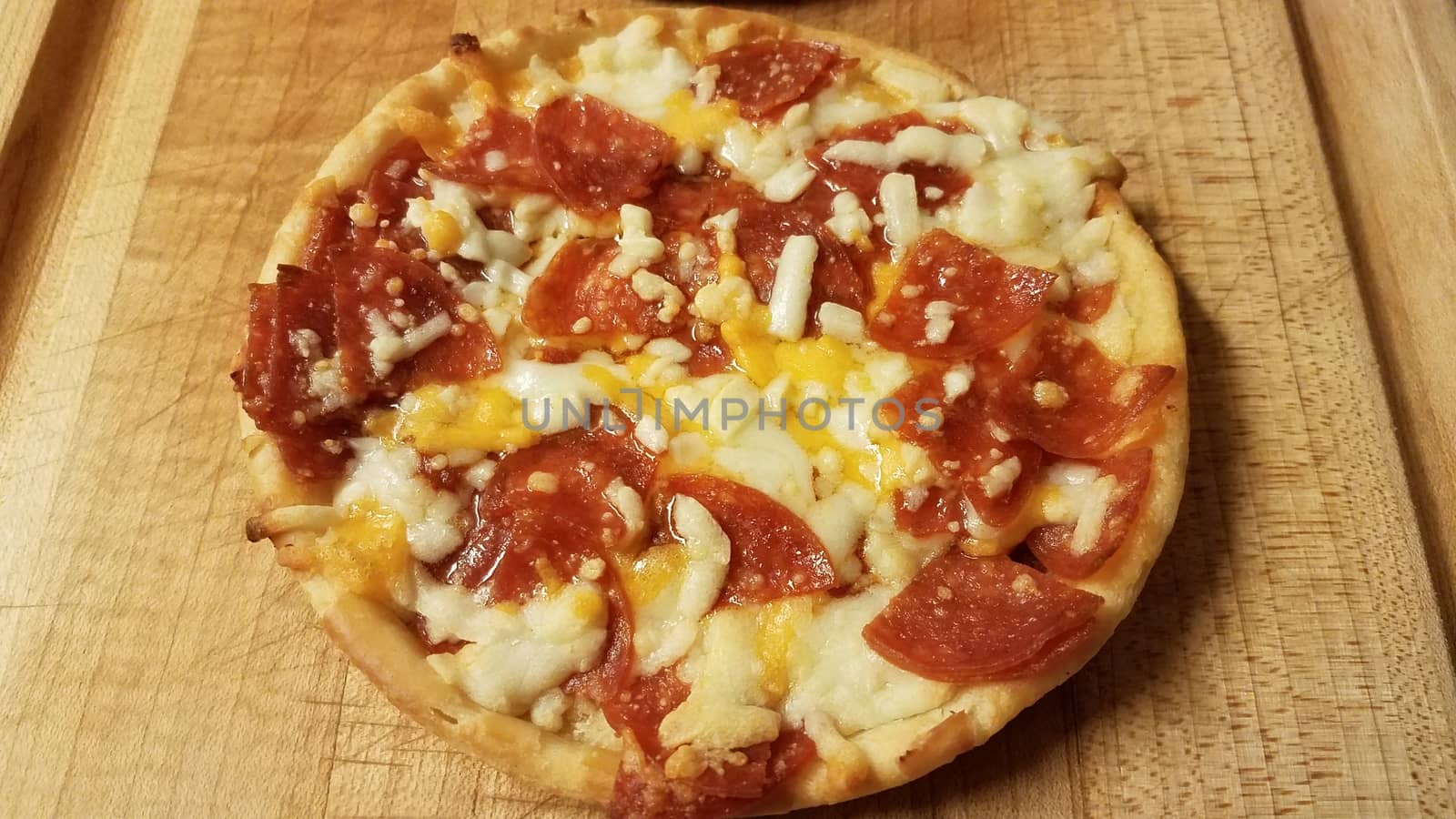 small pepperoni and cheese pizza on cutting board by stockphotofan1