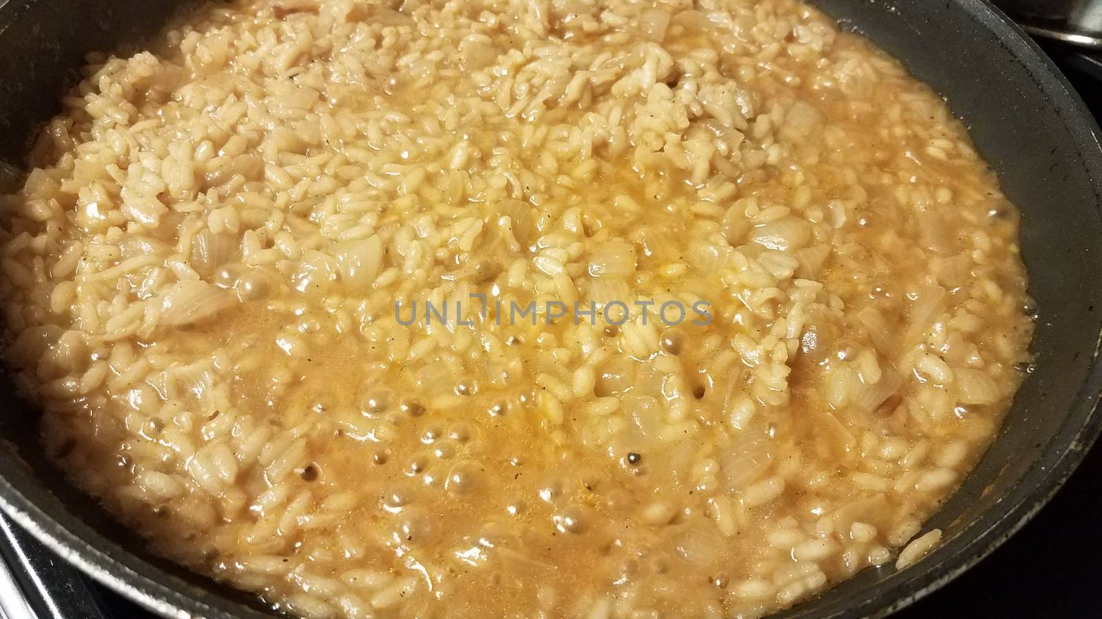 risotto italian rice with gravy and onion in skillet by stockphotofan1