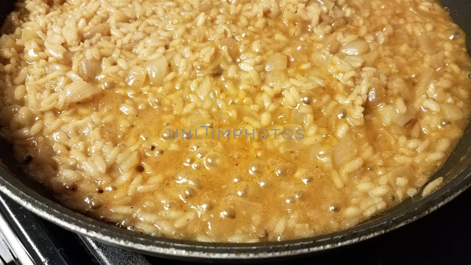 risotto italian rice with gravy and onion in skillet or frying pan