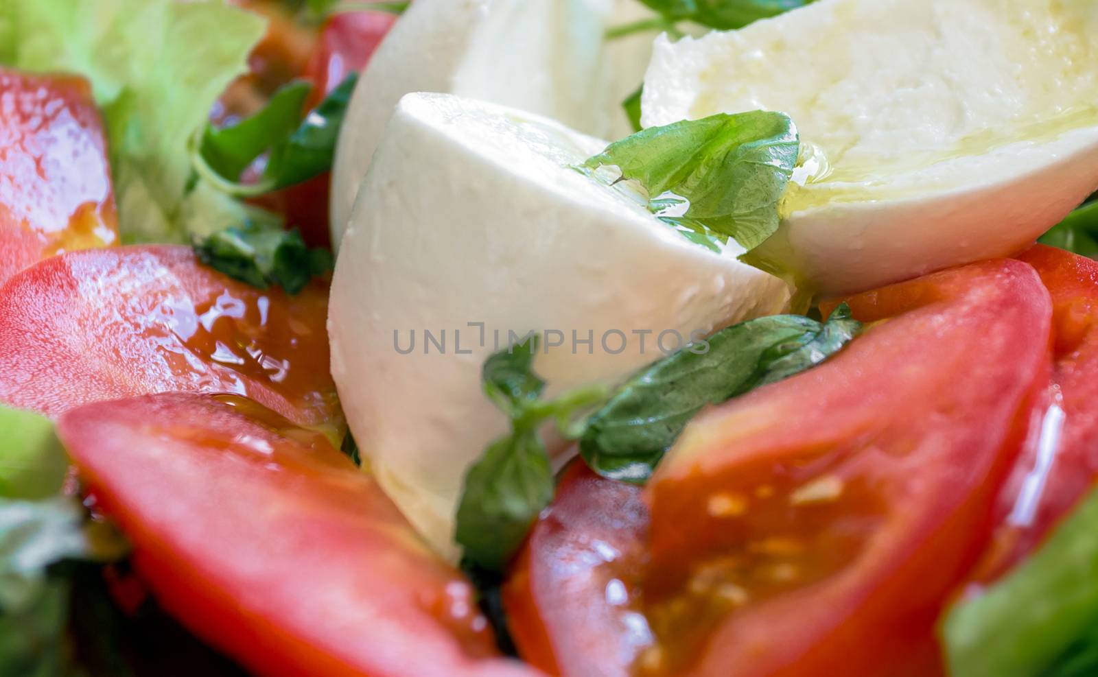 Italian salad. Caprese salad with mozarella cheese, tomatoes and basil. Selective focus. Defocused blurry background.