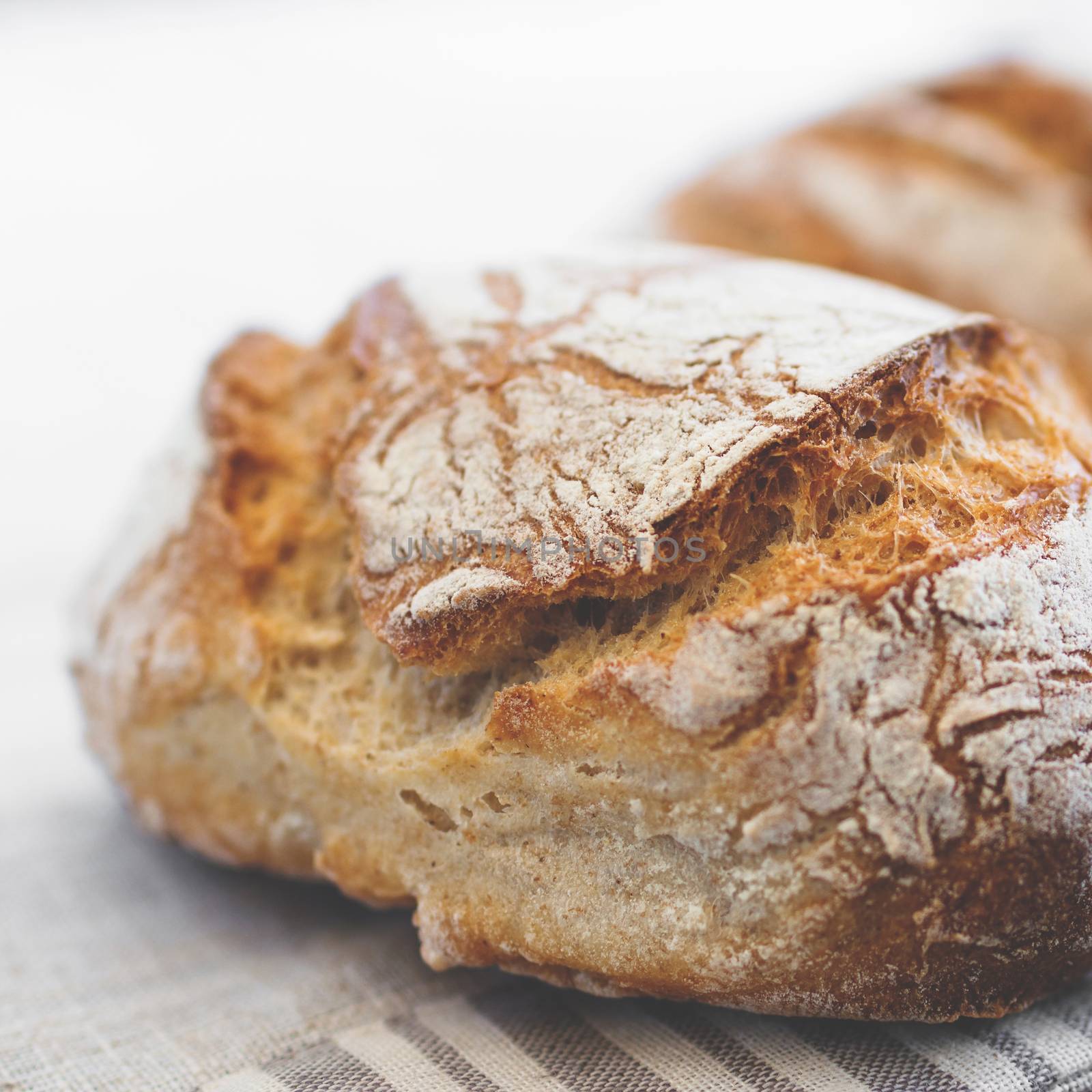 Tasty loaf of bread on table cloth. Extreme close-up of rustic Italian bread. Shallow DOF.