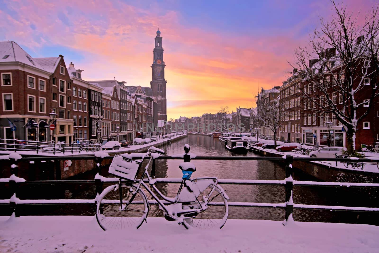 City scenic from snowy Amsterdam with the Westerkerk in the Netherlands at sunset