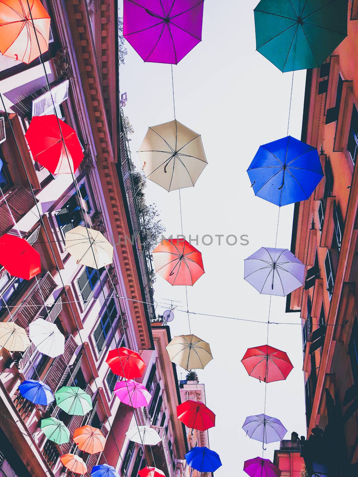 Genova, Italy - 0/29/2020: Multicolored umbrellas against the sky, street decorated. LGBT flag. Rainbow love concept. Human rights and tolerance.