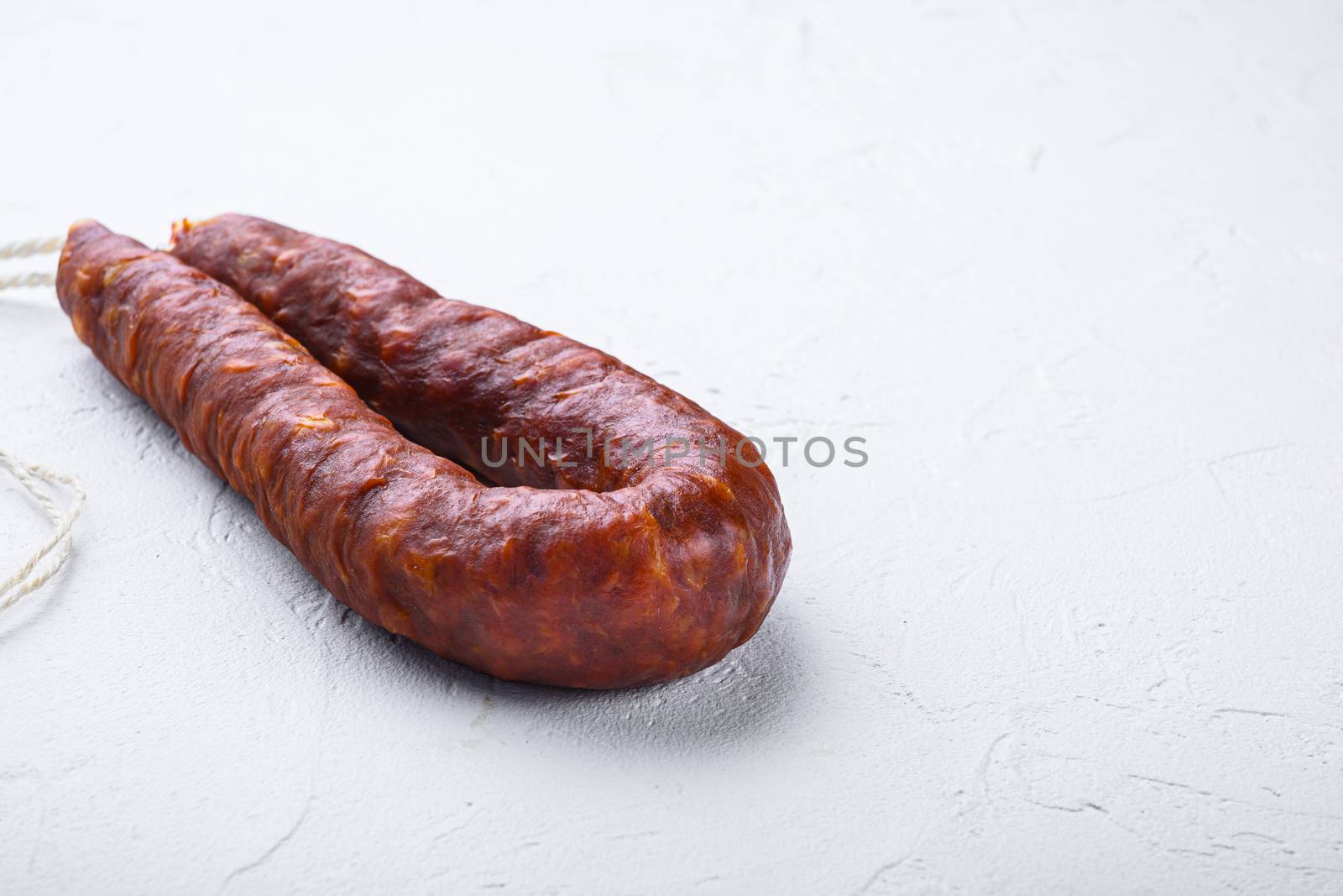 Dry cured chorizo sausage on white textured background with copy space.