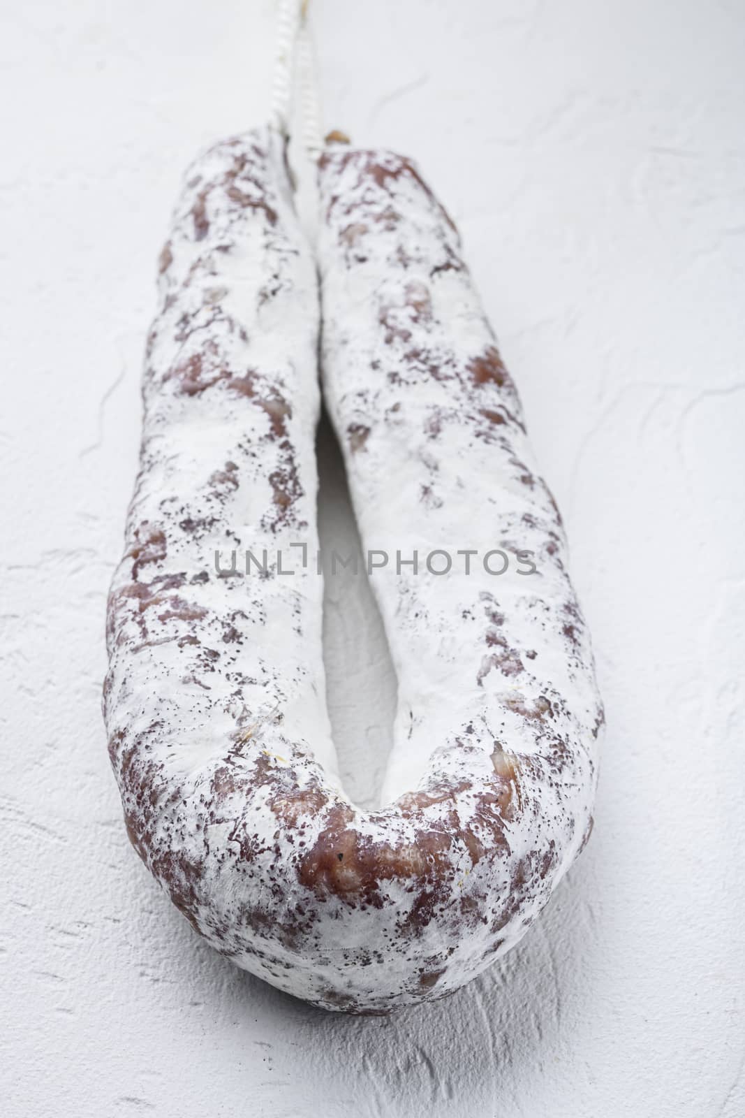 Salami sausage fuet on white textured background.