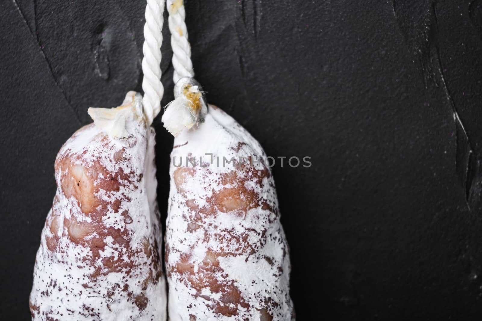 Fuet salami wurst on black surface with copy space.