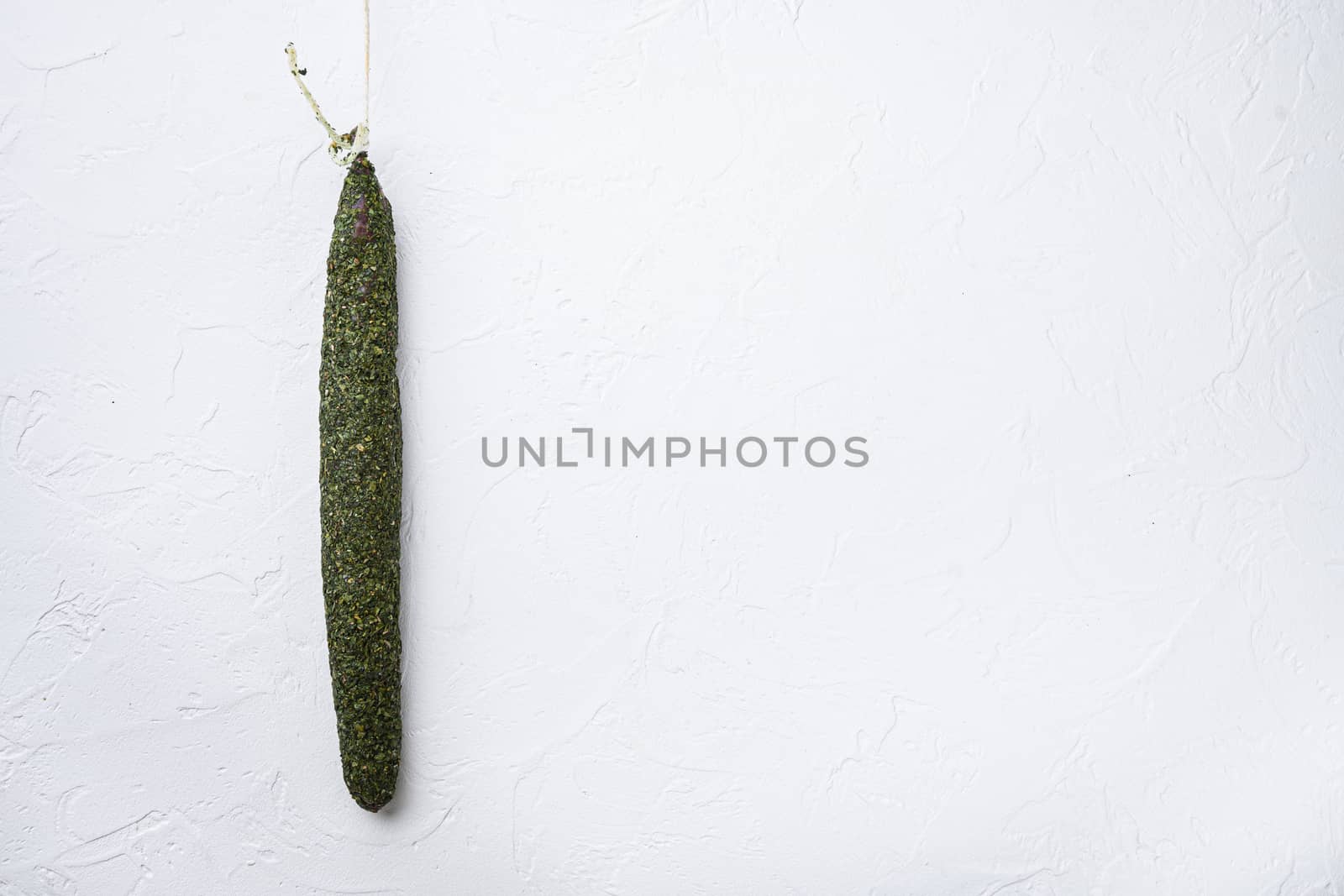 Fuet, salami sausages on white textured background with copy space.