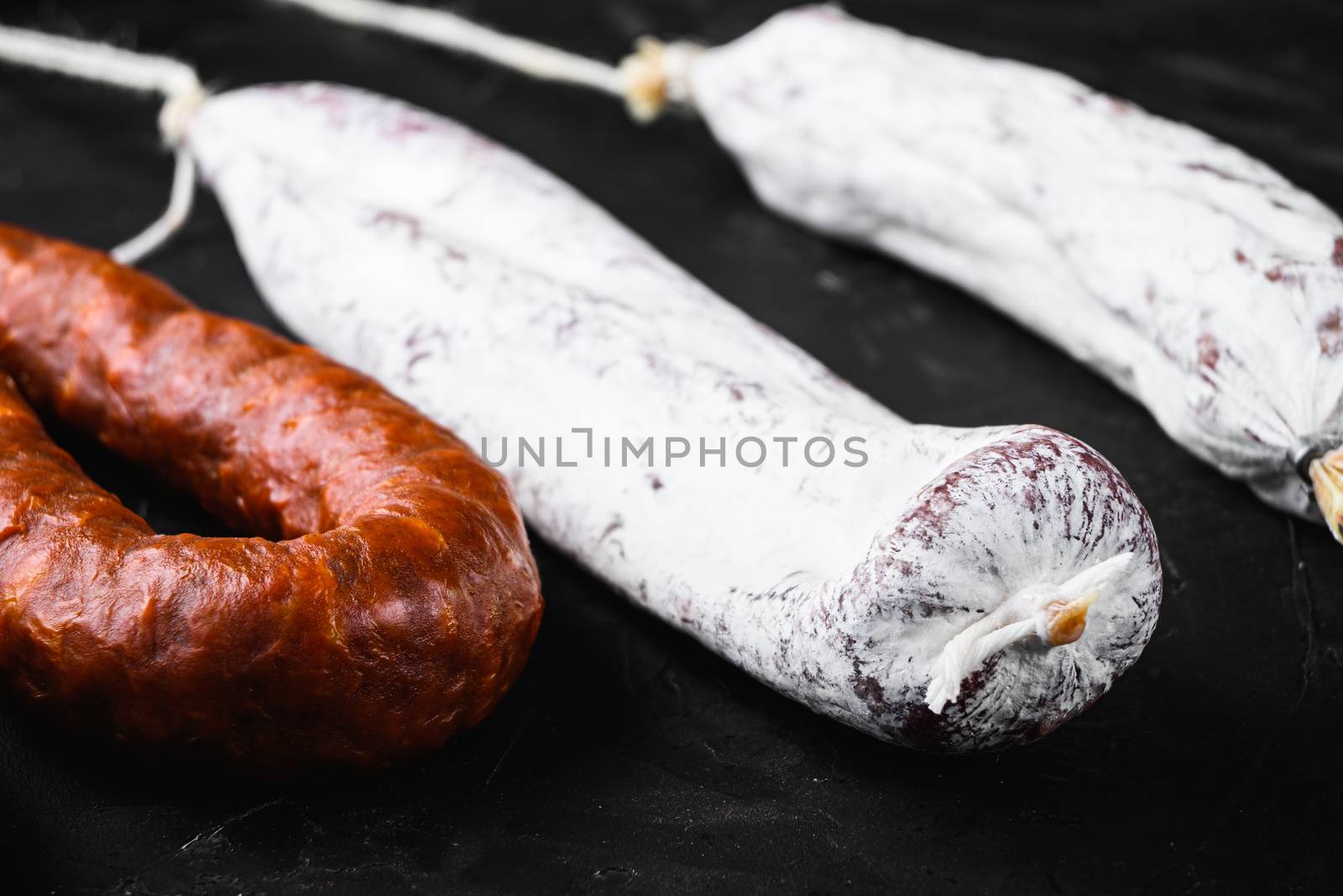 Traditional spanish sausages fuet and chorizo on black surface.