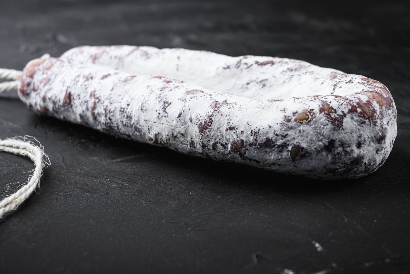 Fuet salami wurst on black background.
