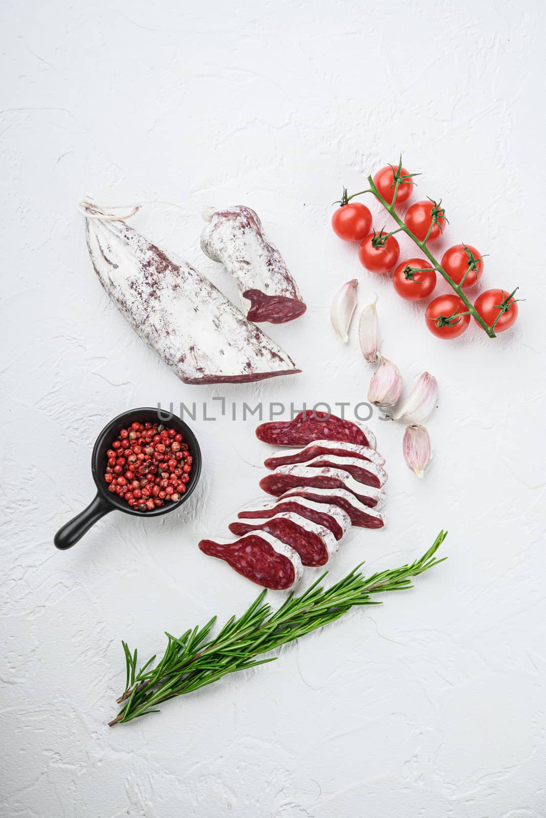 Sliced cuts of longaniza, dry cured spanish sausage with herbs and spices on white textured background.