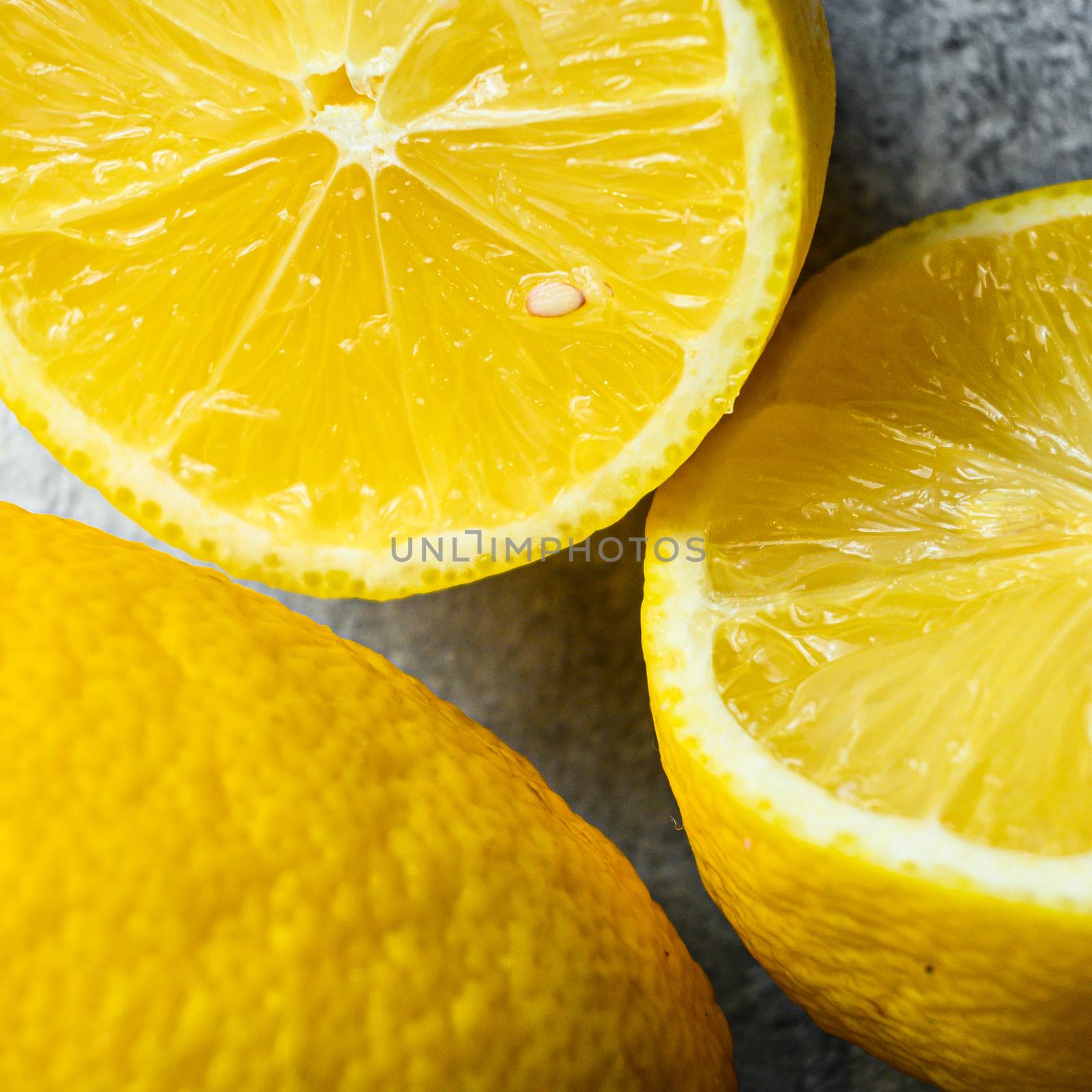 Ripe juicy Lemon curd closeup on gray background. Whole yellow lemon and lemon cut half, top view, vitamin c source.