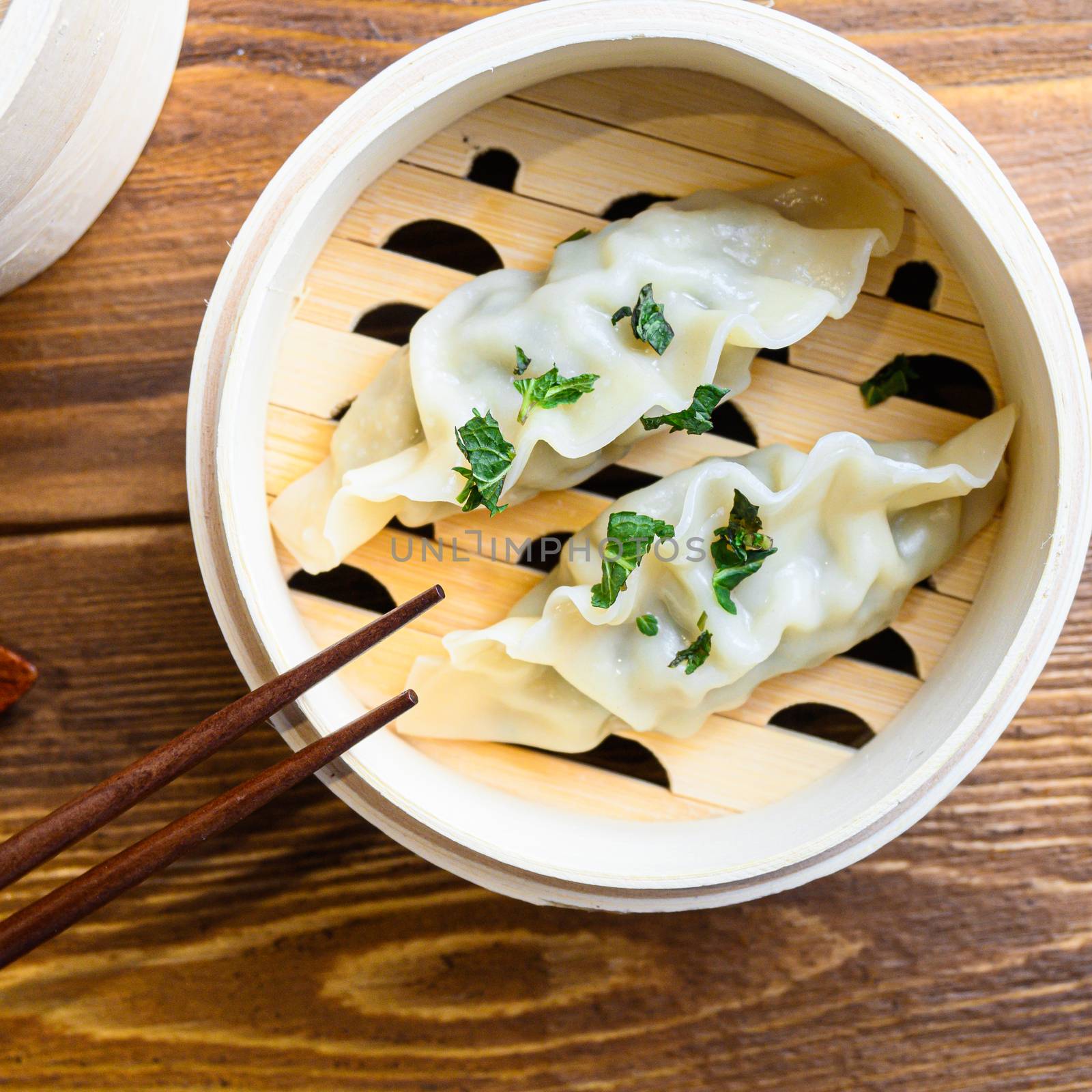 Steam Chinese food of the steaming gyoza close up on wood table by Ilianesolenyi