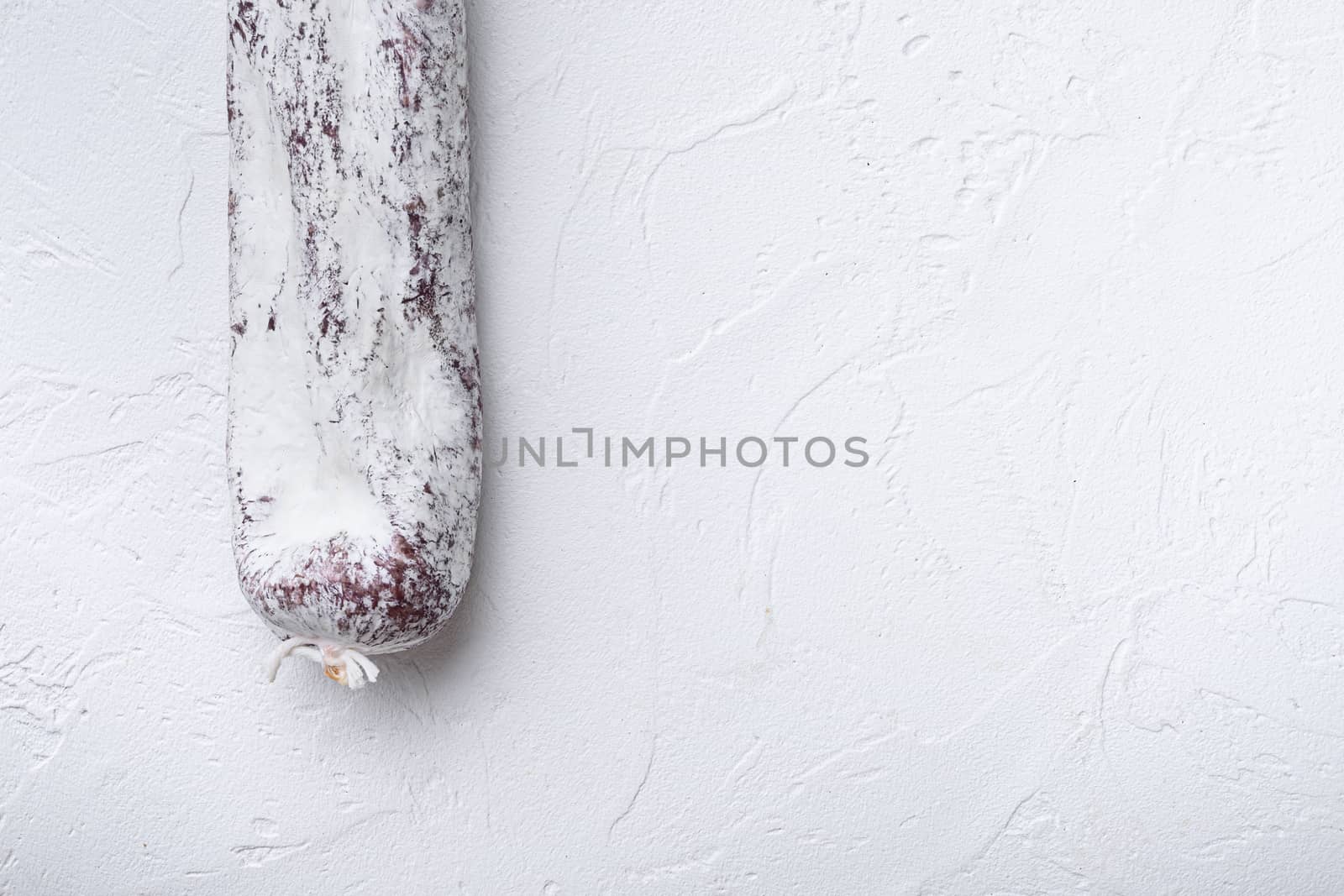 Longaniza spanish salami sausage on white textured background with copy space.