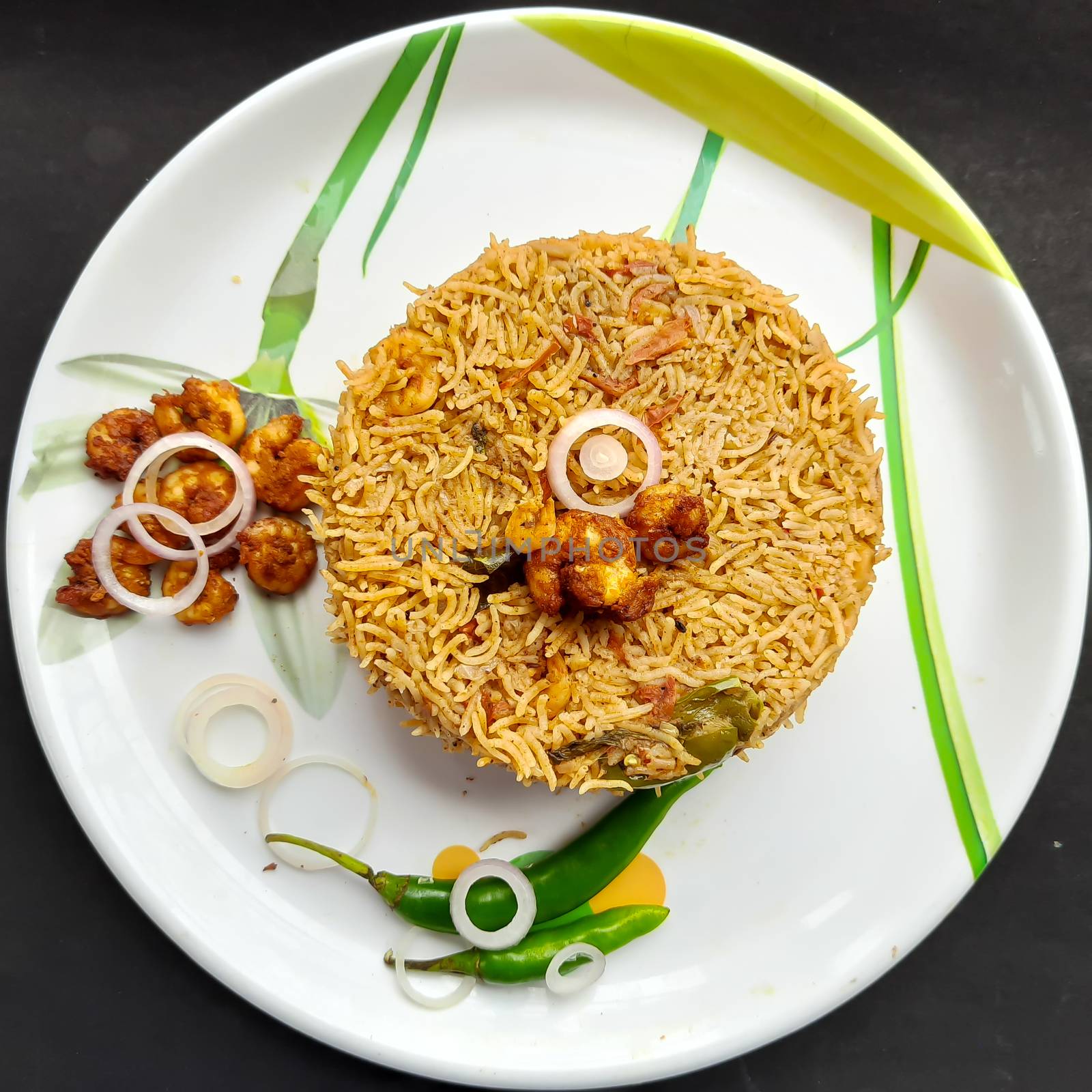 Colorful Delicious yummy prawn briyani with prawn fry in center with prawn fry and raita plated beautifully in white plate with bayleaf and it's one of favorite restaurant cuisine food by AnithaVikram