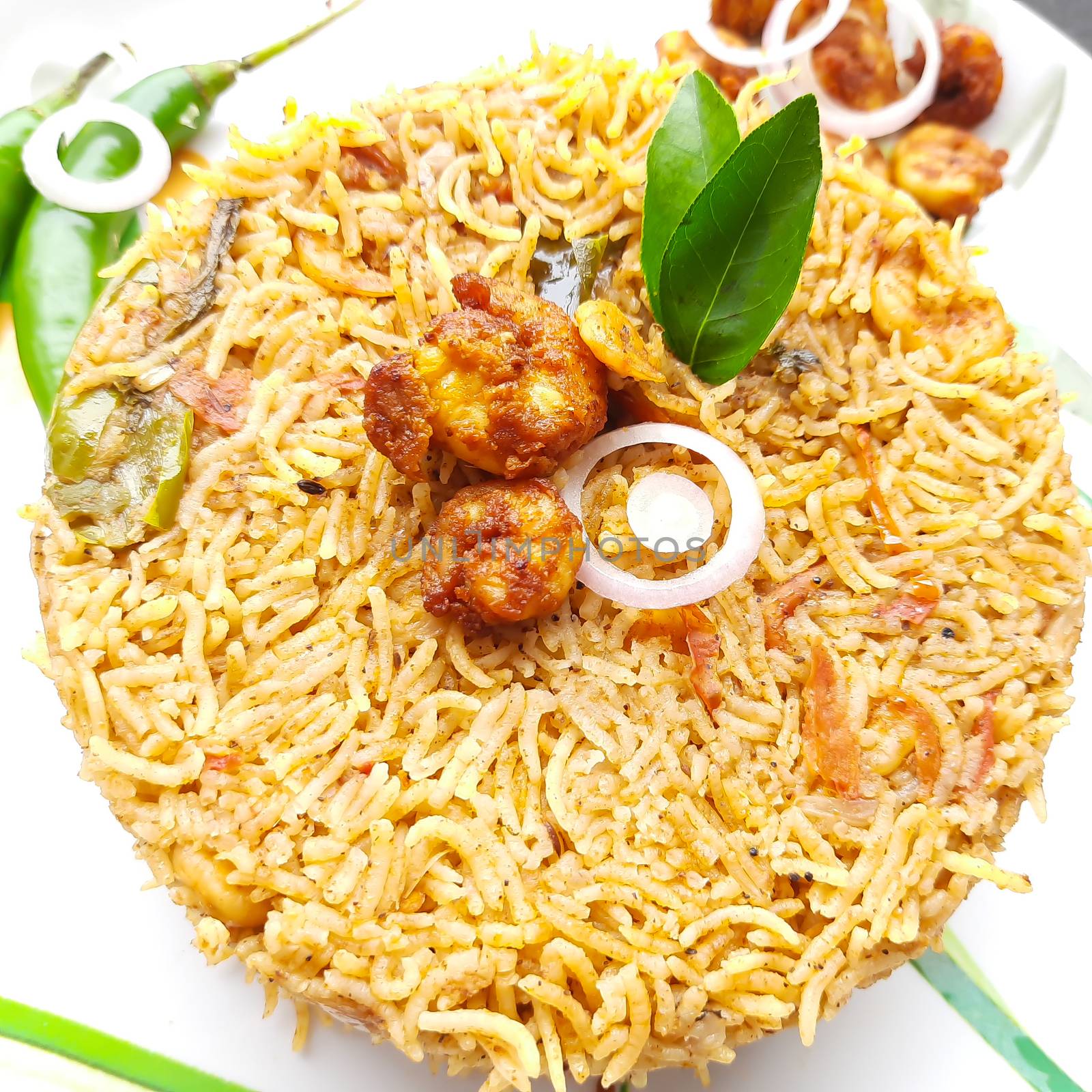 Colorful Delicious yummy prawn briyani with prawn fry in center with prawn fry and raita plated beautifully in white plate with bayleaf and it's one of favorite restaurant cuisine food by AnithaVikram