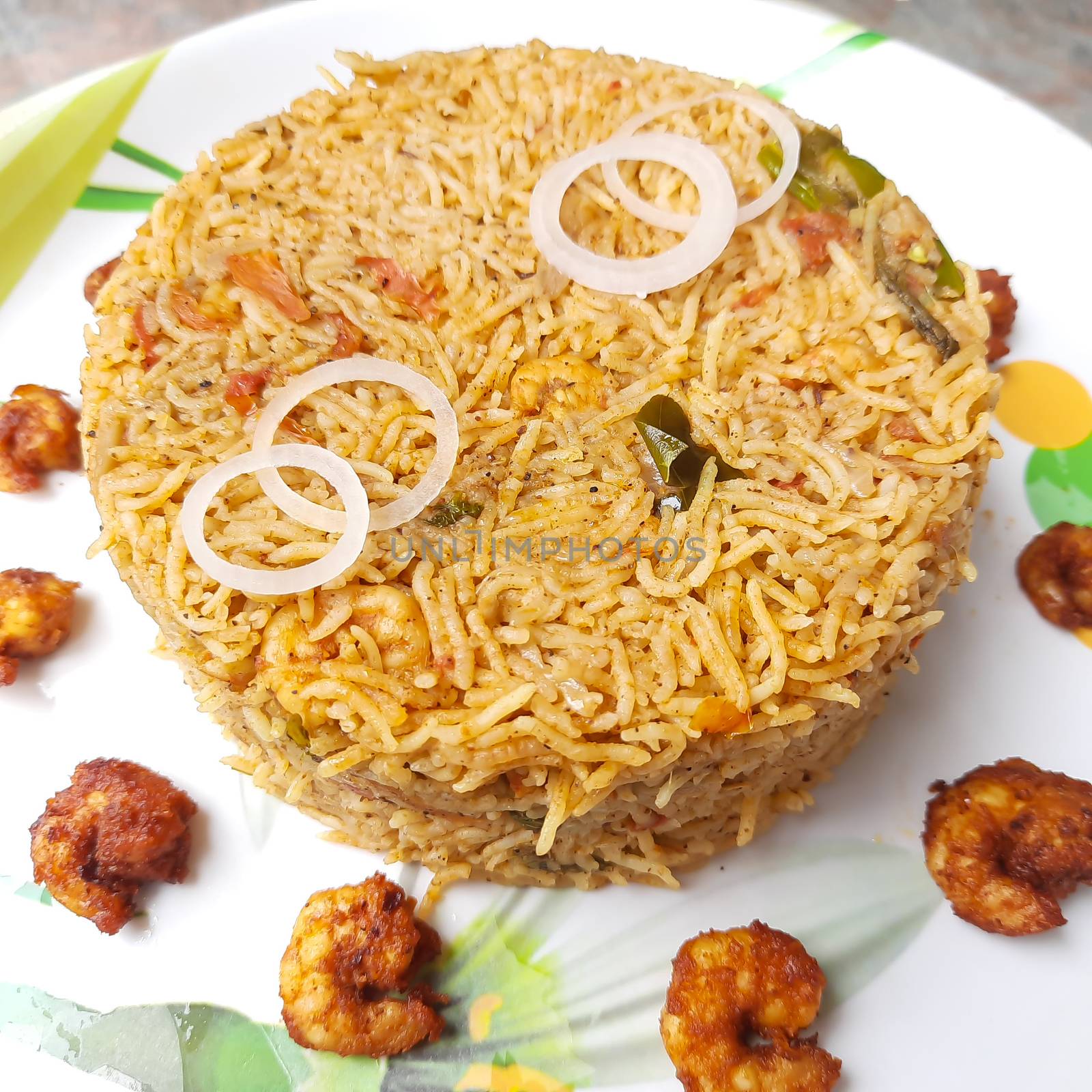 Colorful Delicious yummy prawn briyani with prawn fry in center with prawn fry and raita plated beautifully in white plate with bayleaf and it's one of favorite restaurant cuisine food