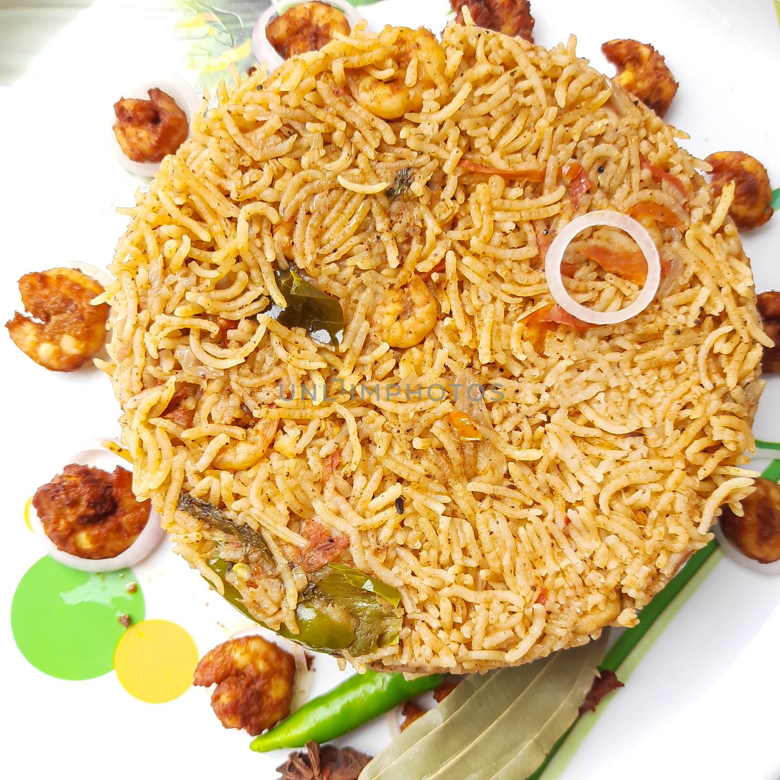 Colorful Delicious yummy prawn briyani with prawn fry in center with prawn fry and raita plated beautifully in white plate with bayleaf and it's one of favorite restaurant cuisine food