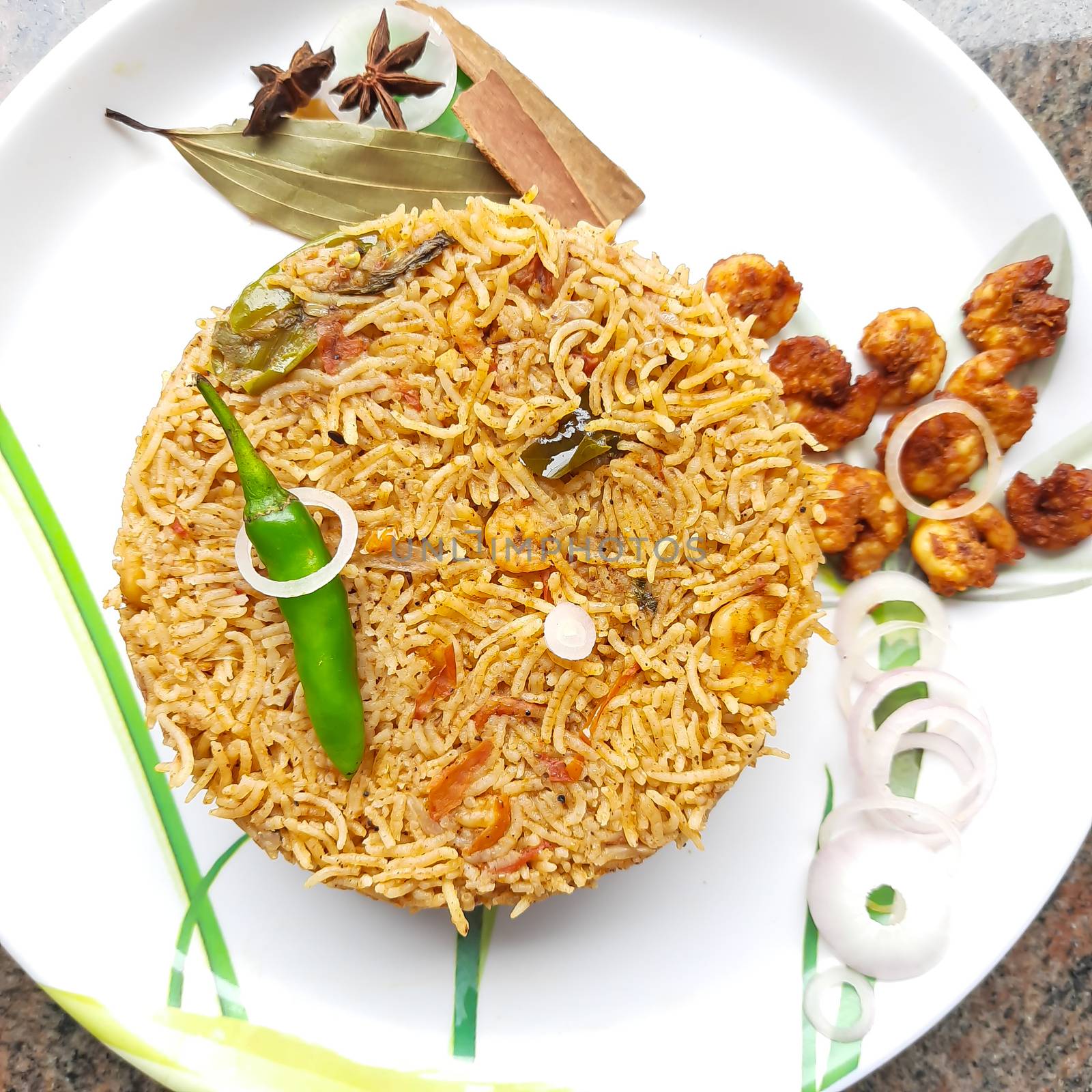 Colorful Delicious yummy prawn briyani with prawn fry in center with prawn fry and raita plated beautifully in white plate with bayleaf and it's one of favorite restaurant cuisine food by AnithaVikram