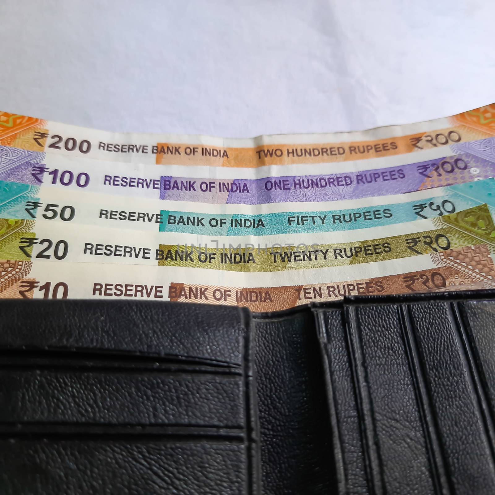 Indian new rupees currency notes arranged orderly number upwards manner with all rupee coins in white paper in wallet