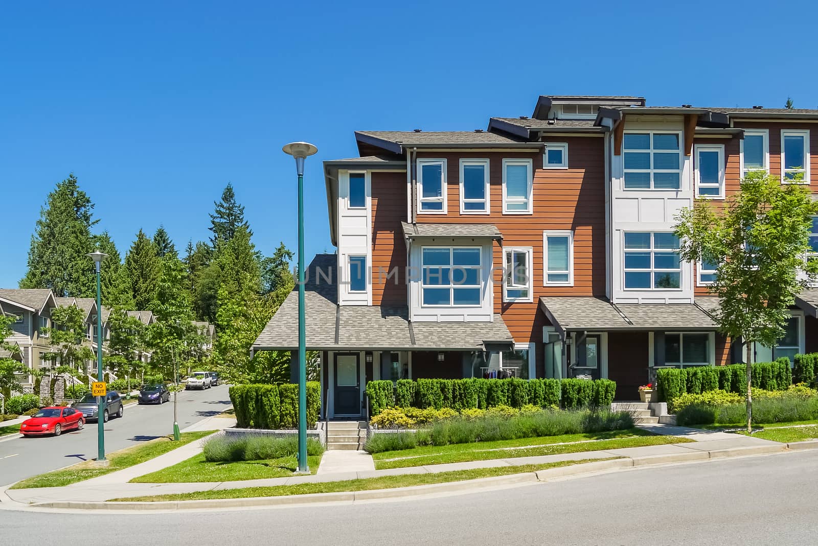 Corner unit of new townhouses with entrance door from the street on bright sunny day