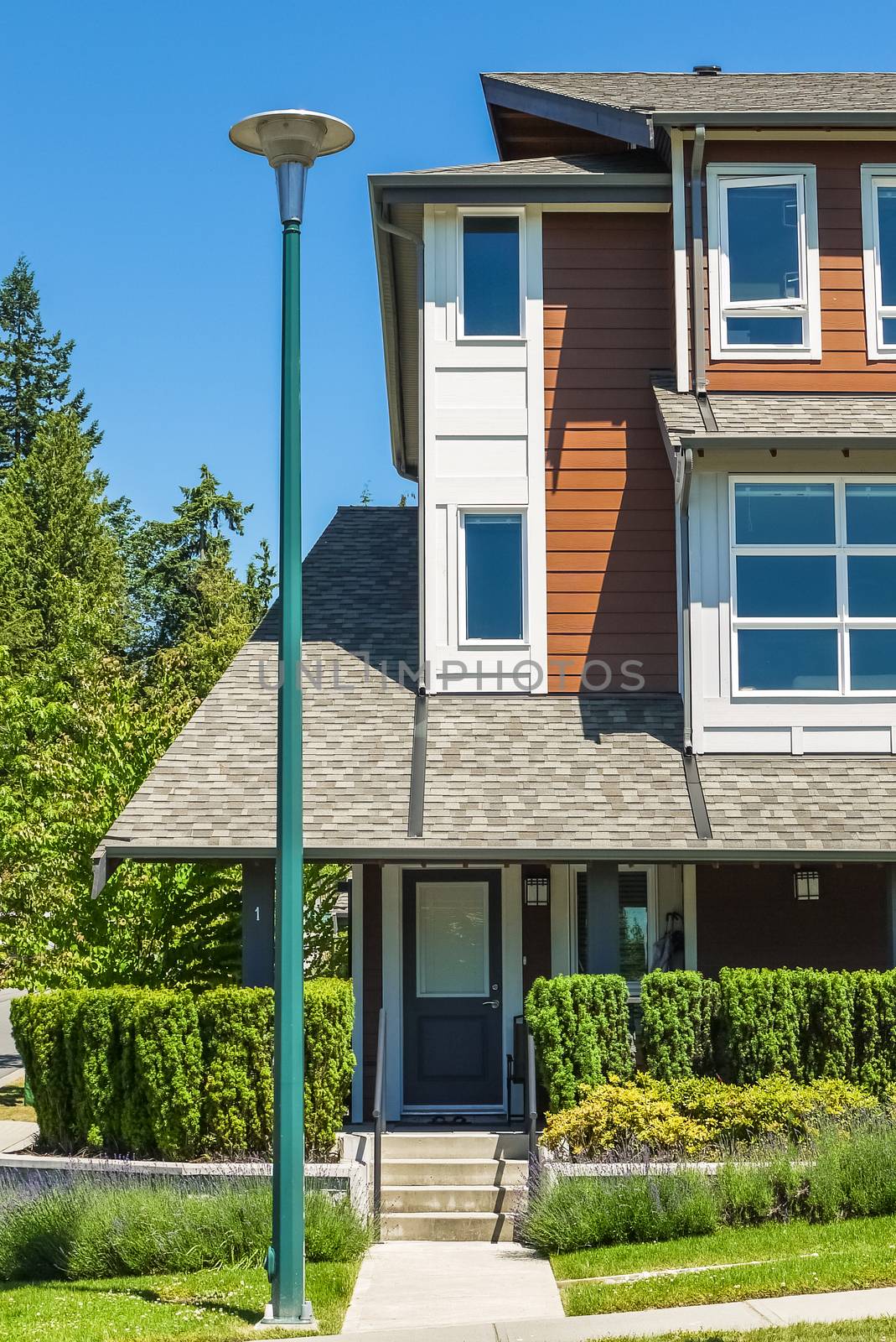 Corner of new townhouses with entrance door and street light pole in front on bright sunny day