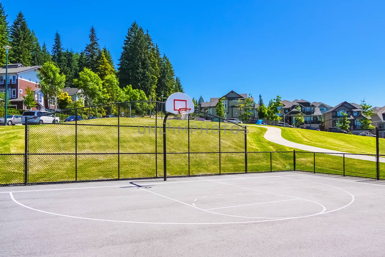 Basketball court within big park area in residential neighborhood