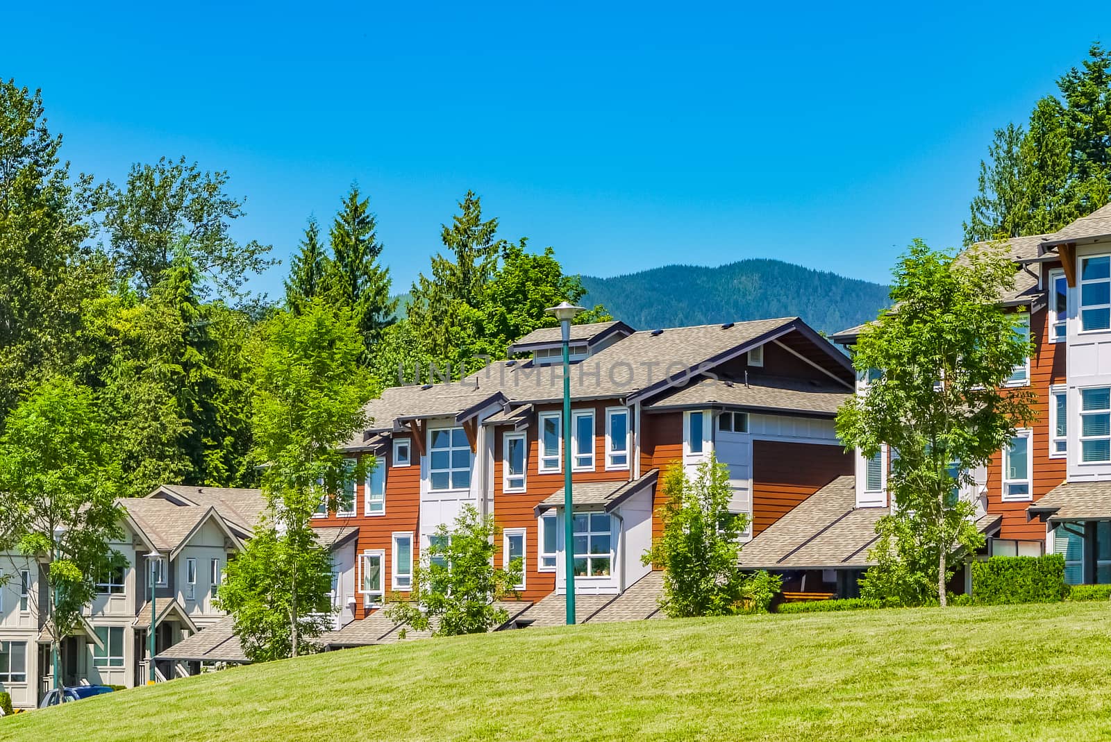 Street of residential townhouses on sunny day with mountain view and blue sky background