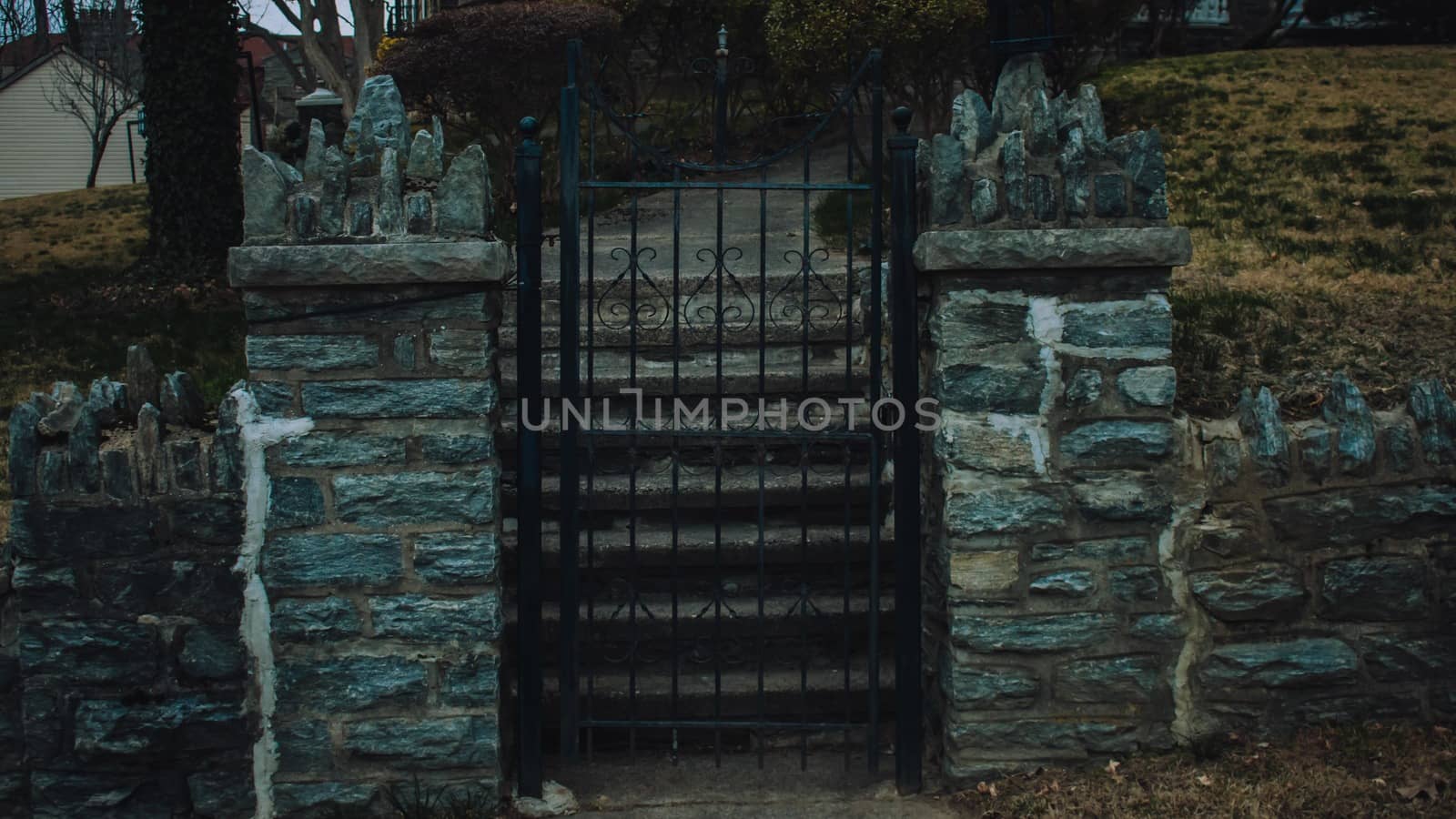 A Detailed Black Metal Fence Between Two Cobblestone Pillars