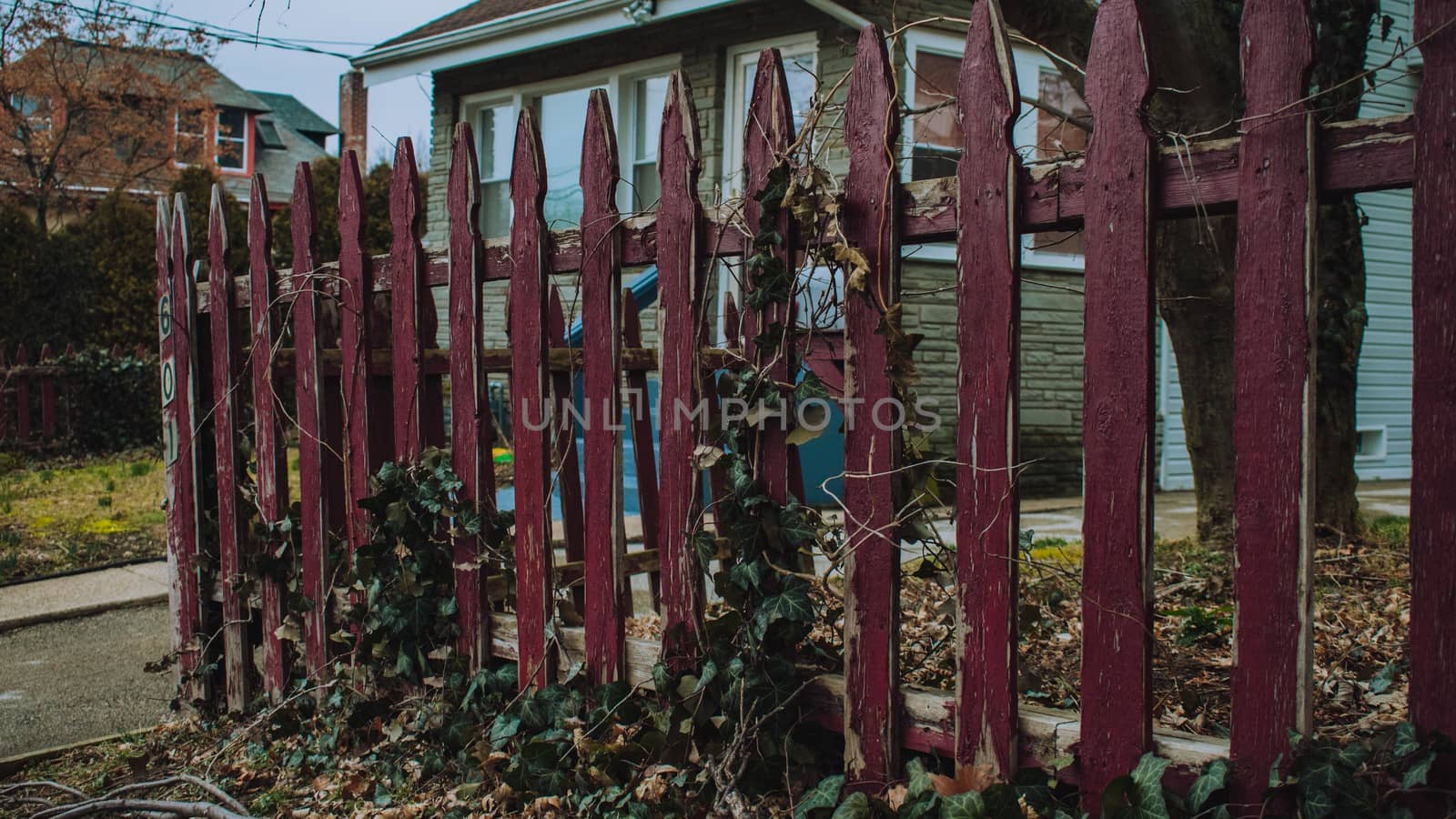 An Old and Weathered Red Wooden Fence Out Front of a House