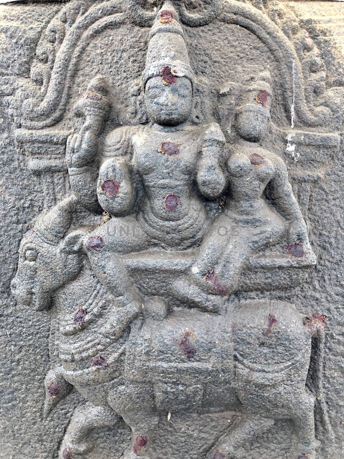 Lord Shiva and Parvati sitting at the top of a bull sculpture. Bas relief sculpture carved in the stone walls of Shiva temple, Tamil nadu by prabhakaran851