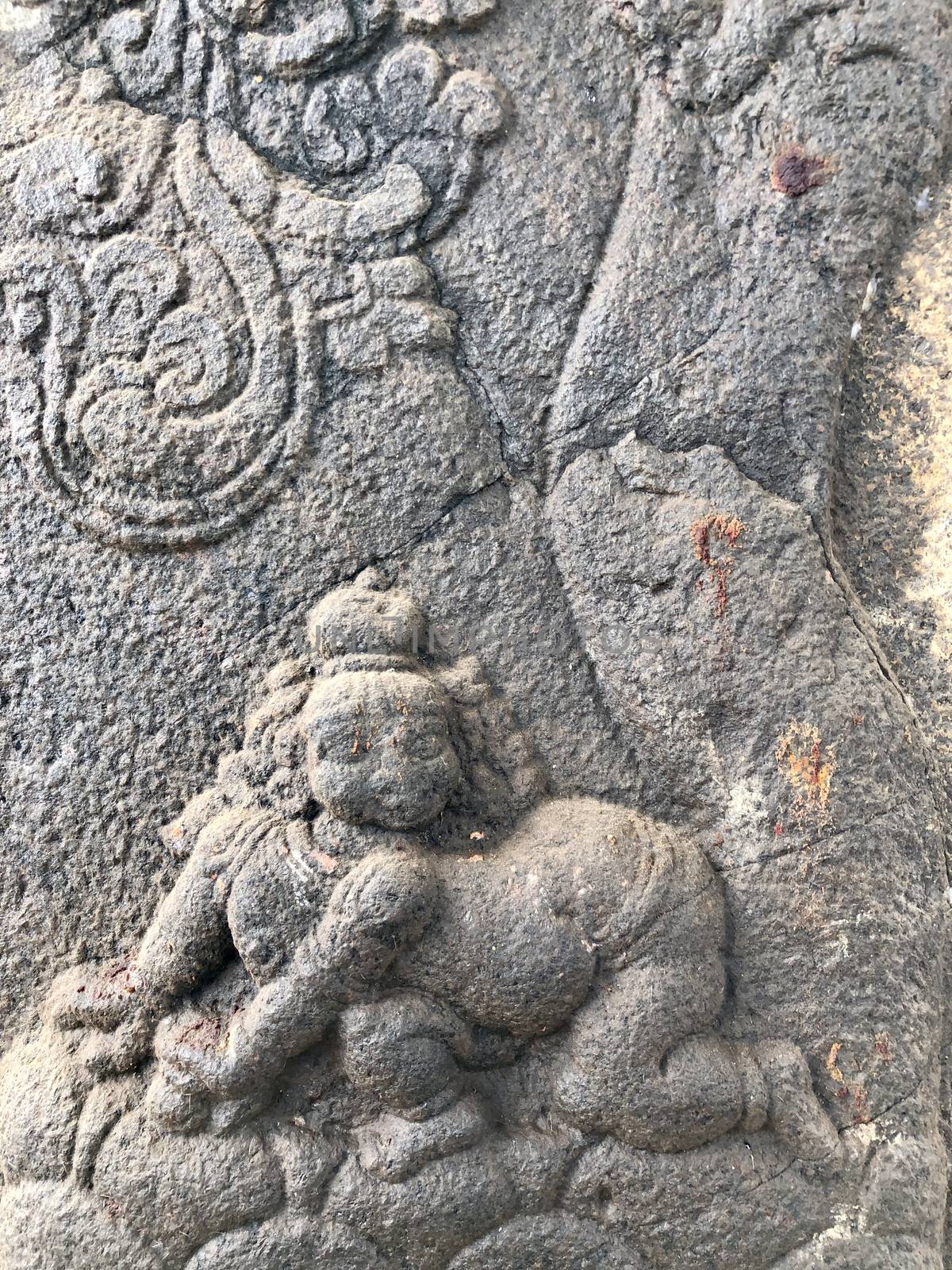 Sculpture of a baby lying in the bottom of a tree. Bas relief sculpture carved in the stone walls of Shiva temple in Tamil nadu. by prabhakaran851