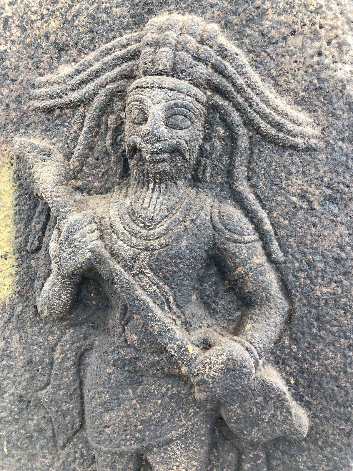 Man with a weapon in hand sculpture. Bas relief sculpture carved in the walls of Shiva temple, Tamil nadu by prabhakaran851