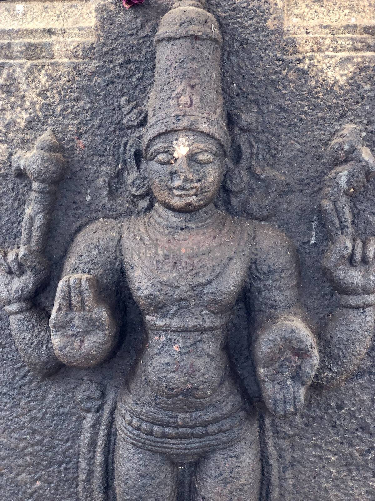 Hindu God sculpture with four hands. Bas relief sculpture carved in the stone wall of Shiva temple, Tamil nadu by prabhakaran851