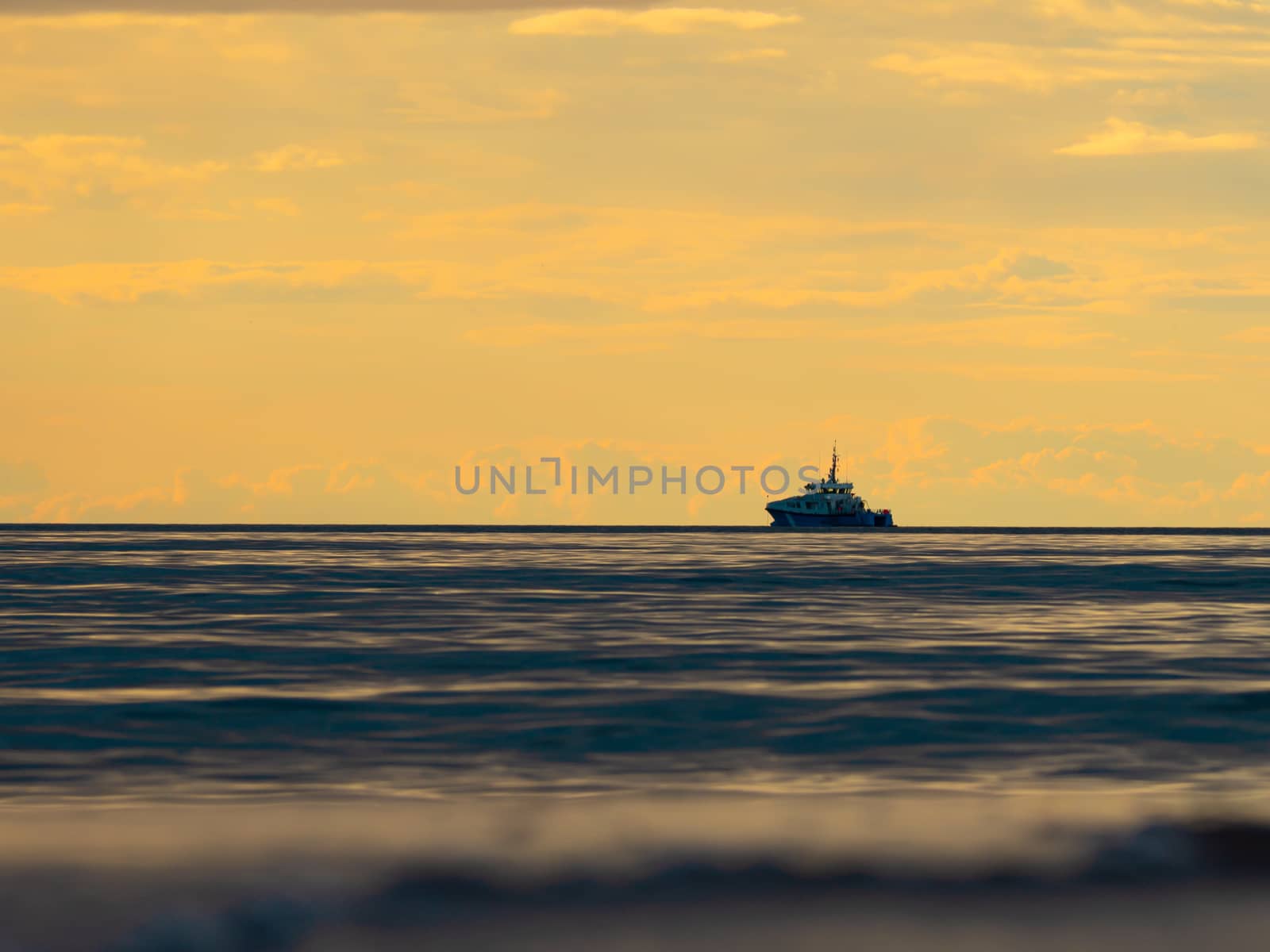 One small fishing boat heading out on the foggy ocean at dawn. Boat on the background of sunset. The Baltic Sea close up, stormy dramatic dark clouds. The Vacation, summer concept