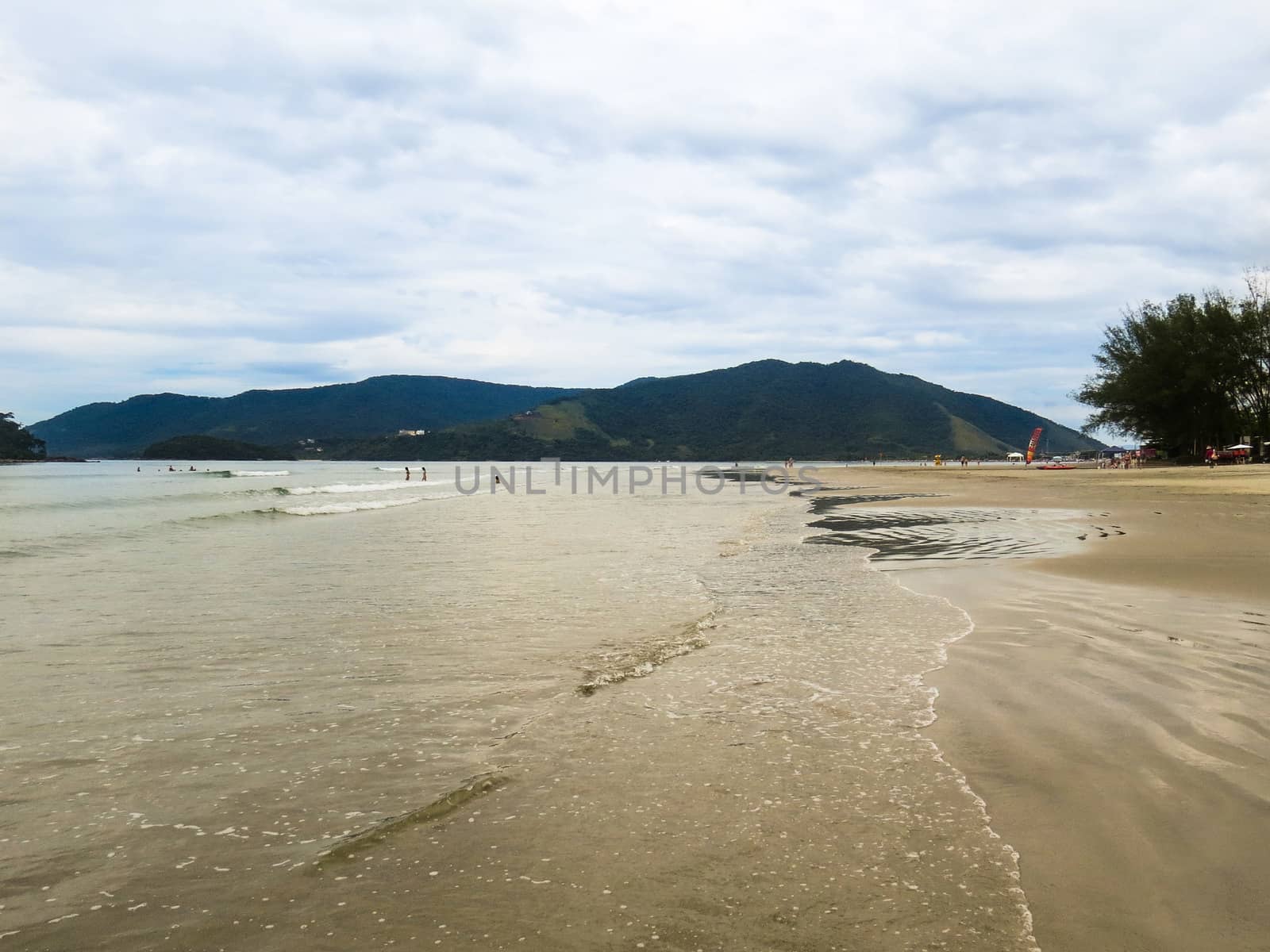 Quiet beach without waves with a wide strip of sand. At the end of the afternoon.