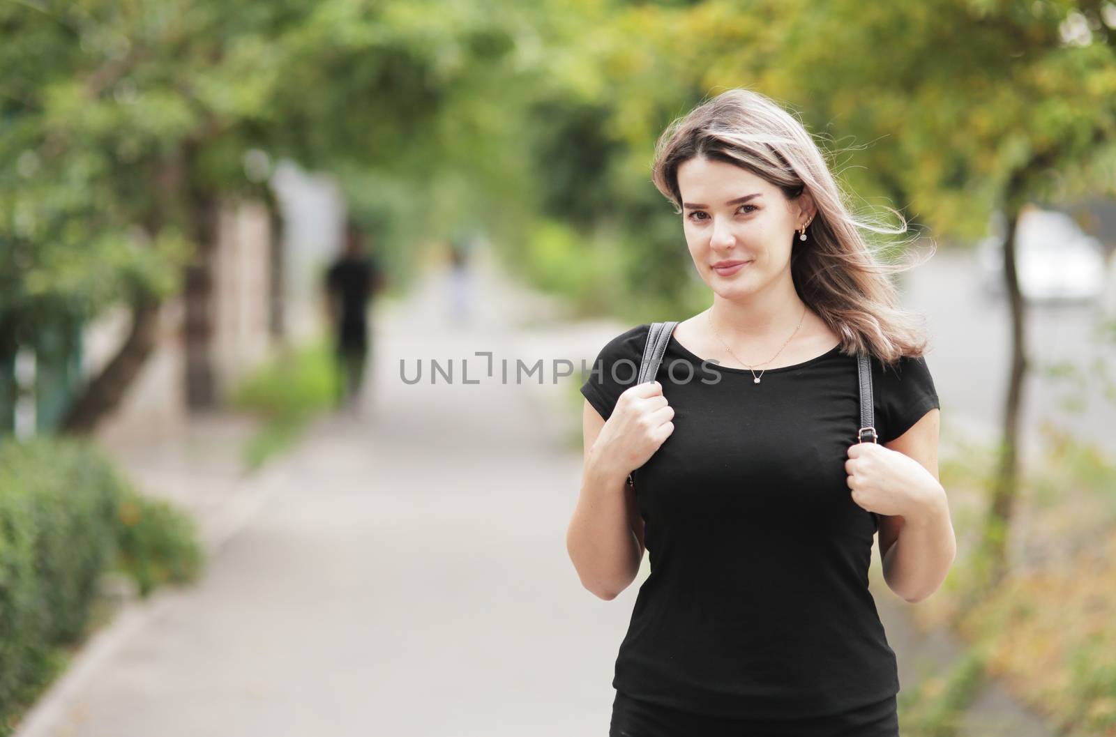 Portrait of a young stylish woman walking down the street with a backpack. by selinsmo